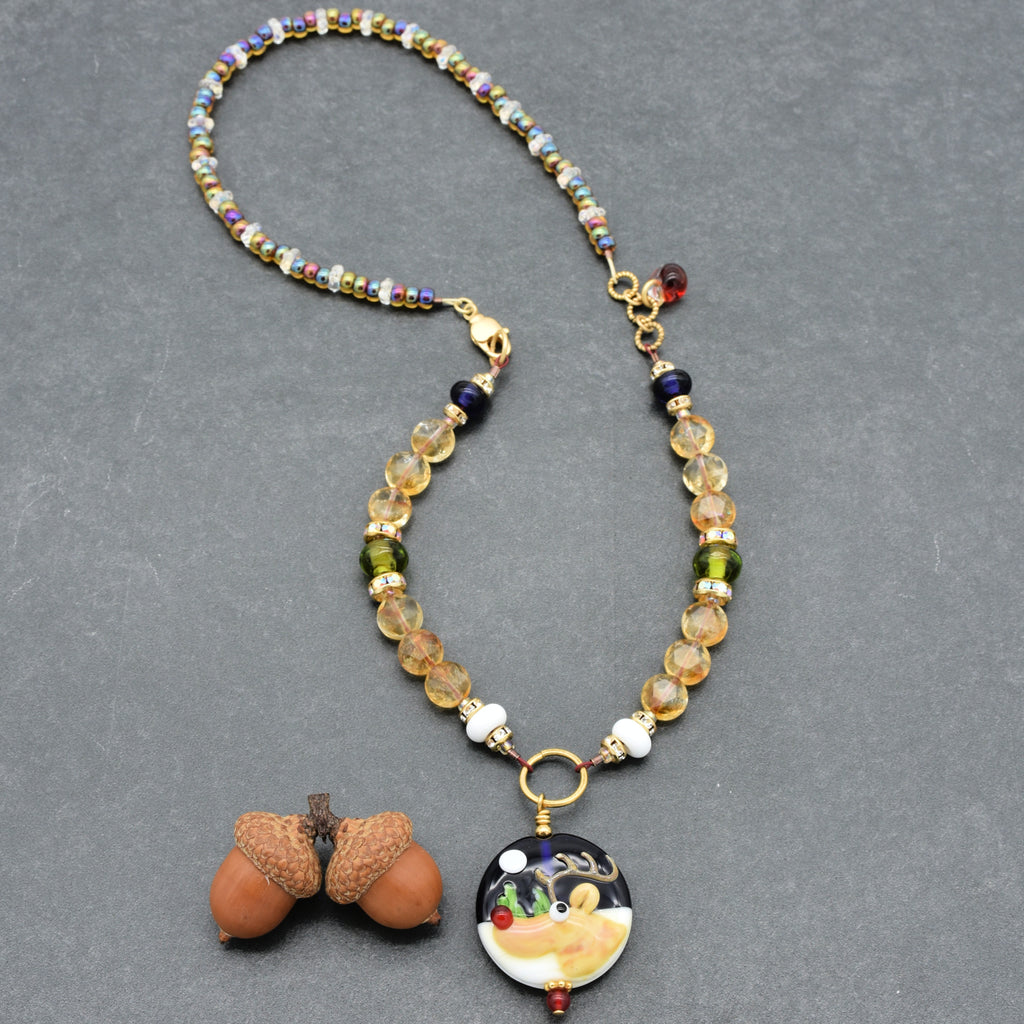 Necklace with a reindeer pendant on a gray background.