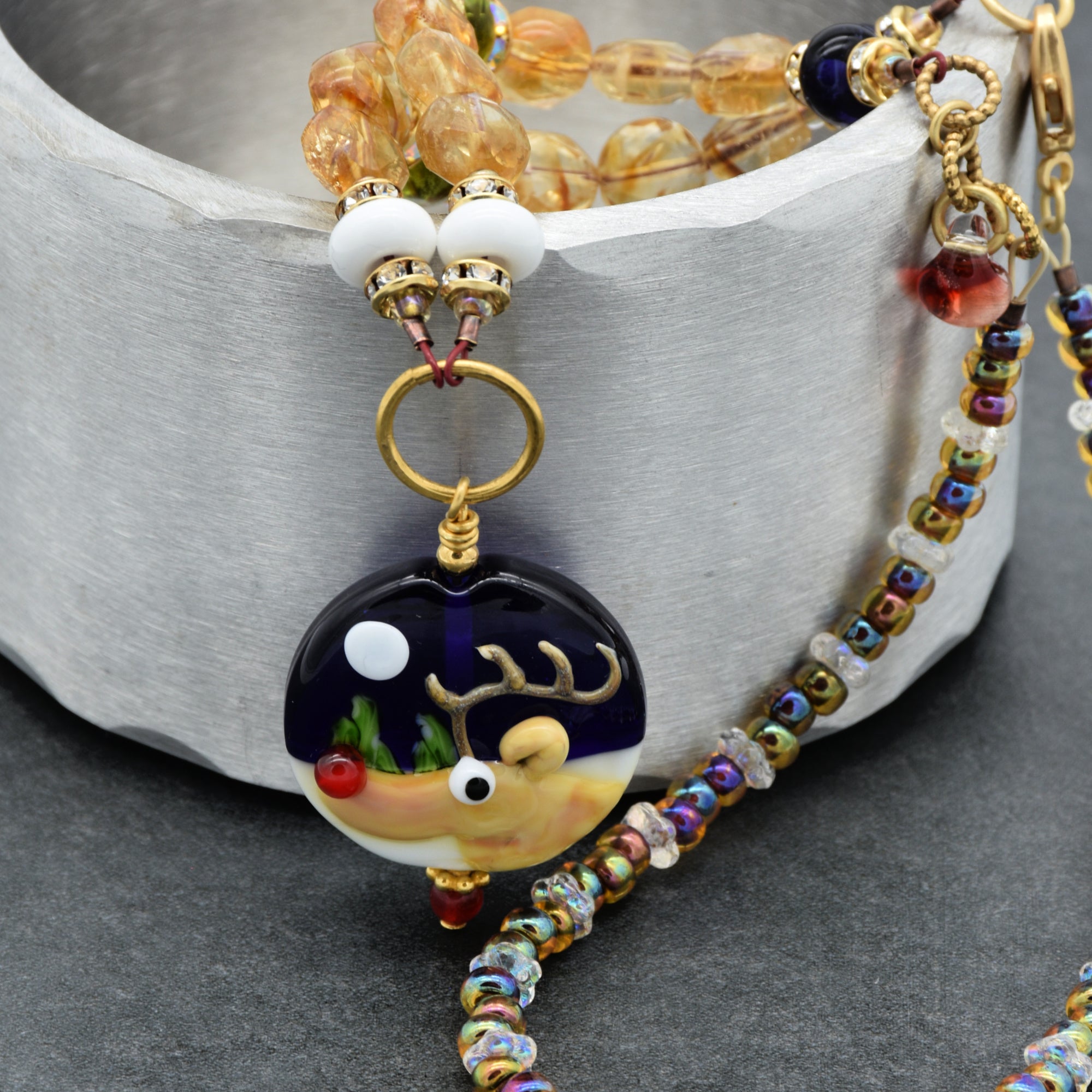 Colorful beaded necklace with a reindeer pendant on a gray surface