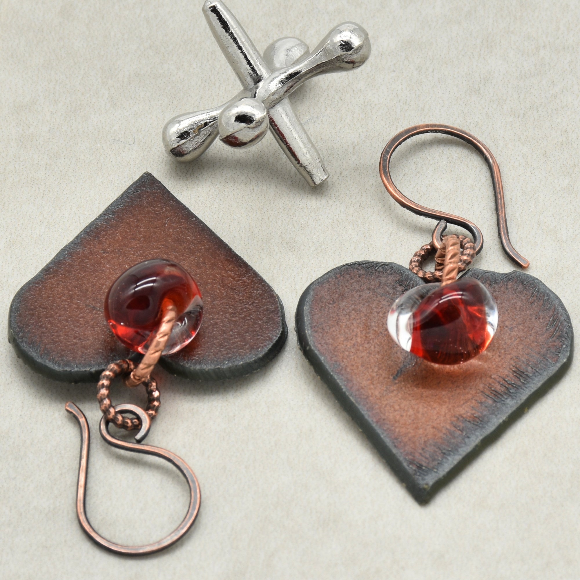 Heart-shaped earrings with red glass charms on a light background