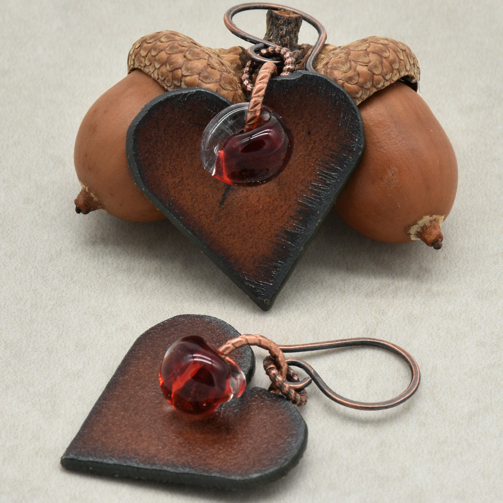 Heart-shaped earrings with red charms on a beige background