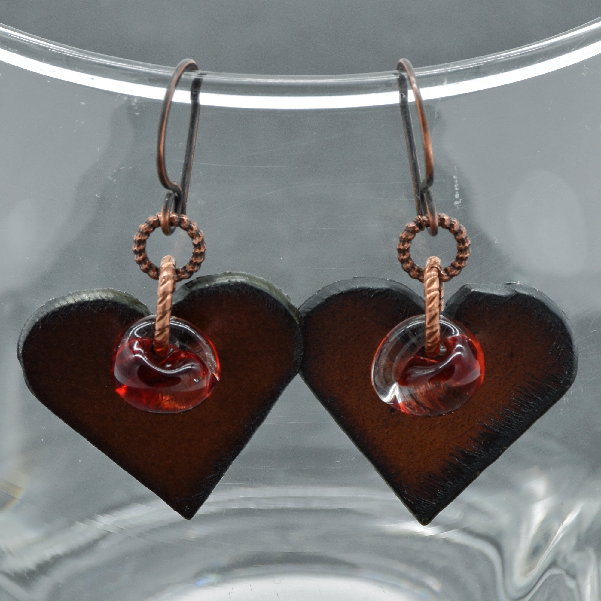 Heart-shaped earrings with red glass charms on a clear background