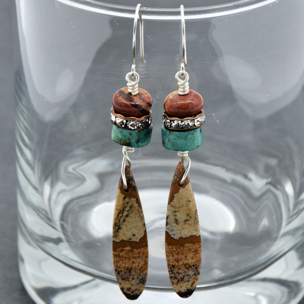 The image shows a pair of earrings. They have hooks for pierced ears and feature multiple beads and stones in their design.