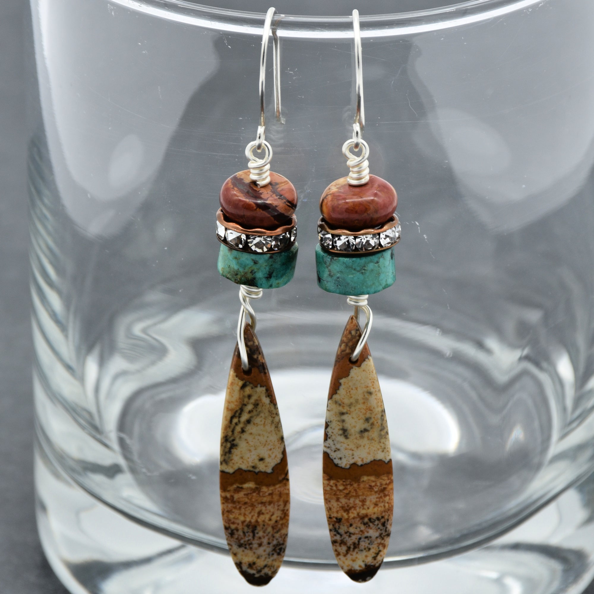 The image shows a pair of earrings. They have hooks for pierced ears and feature multiple beads and stones in their design.