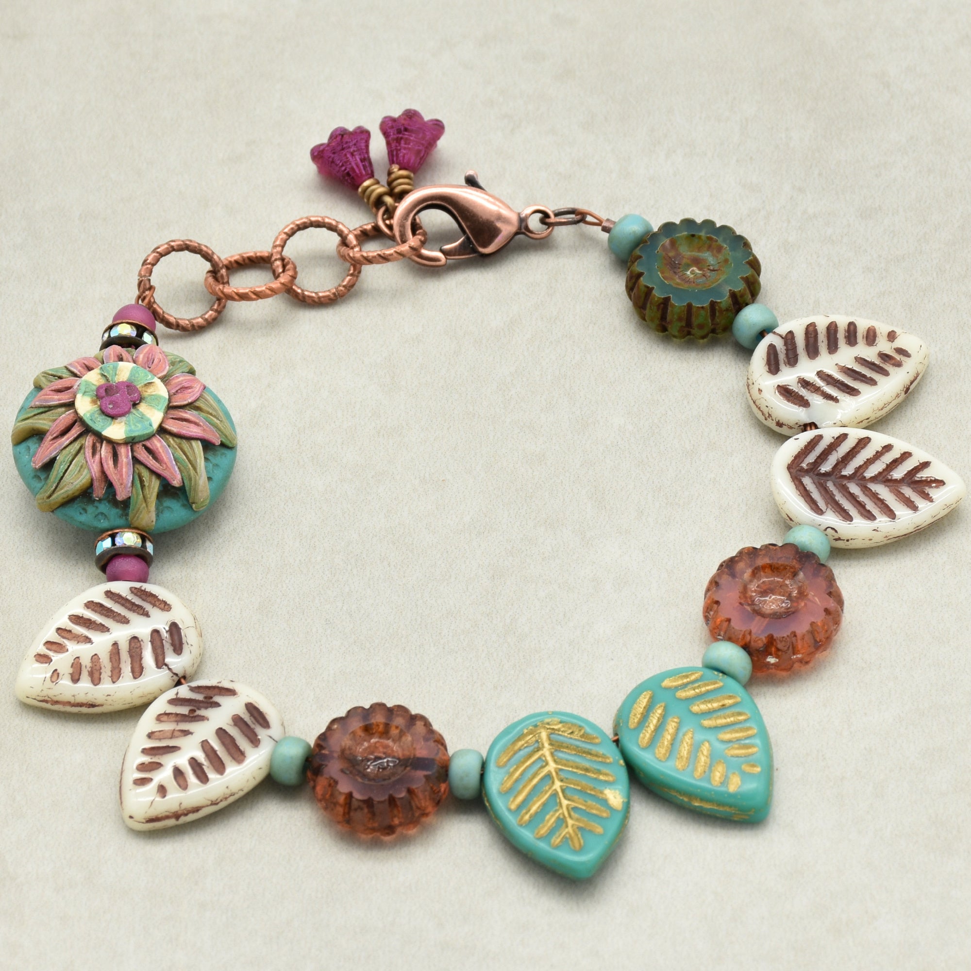 Colorful beaded bracelet with floral and leaf designs on a light background
