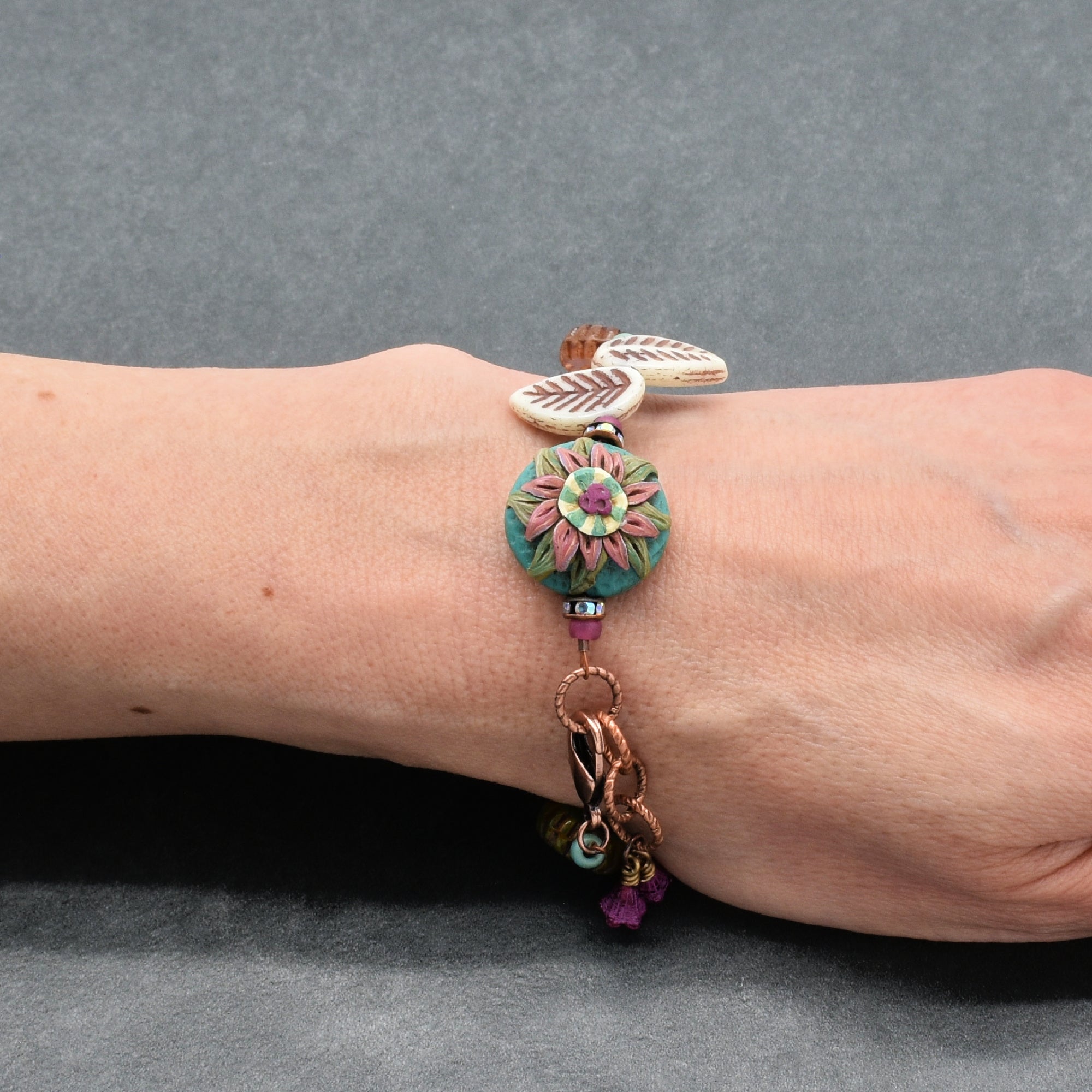 Colorful bracelet with floral design on a wrist against a gray background