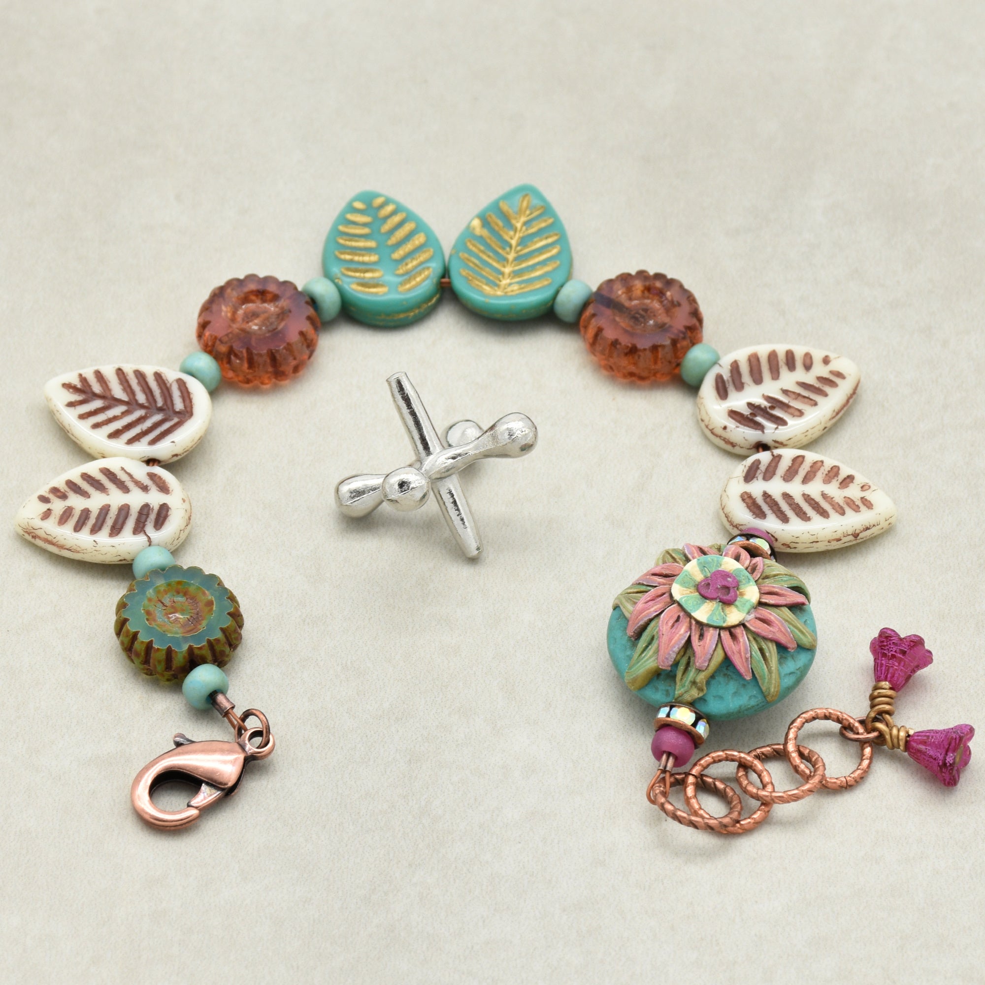 Colorful beaded bracelet with various charms on a light background