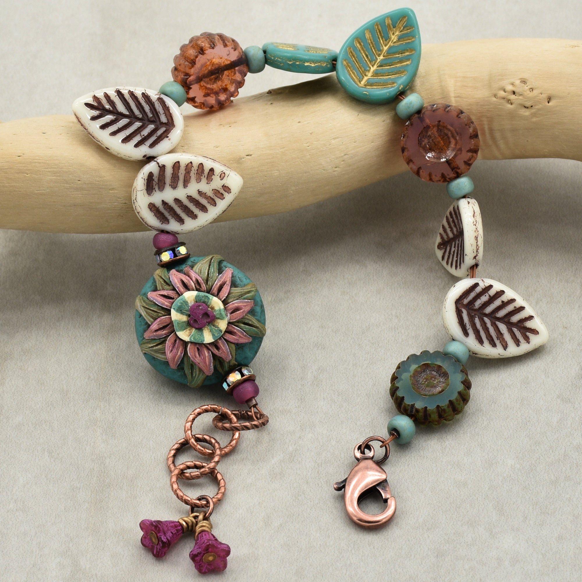 Colorful beaded bracelet with leaf and flower designs on a wooden stick.
