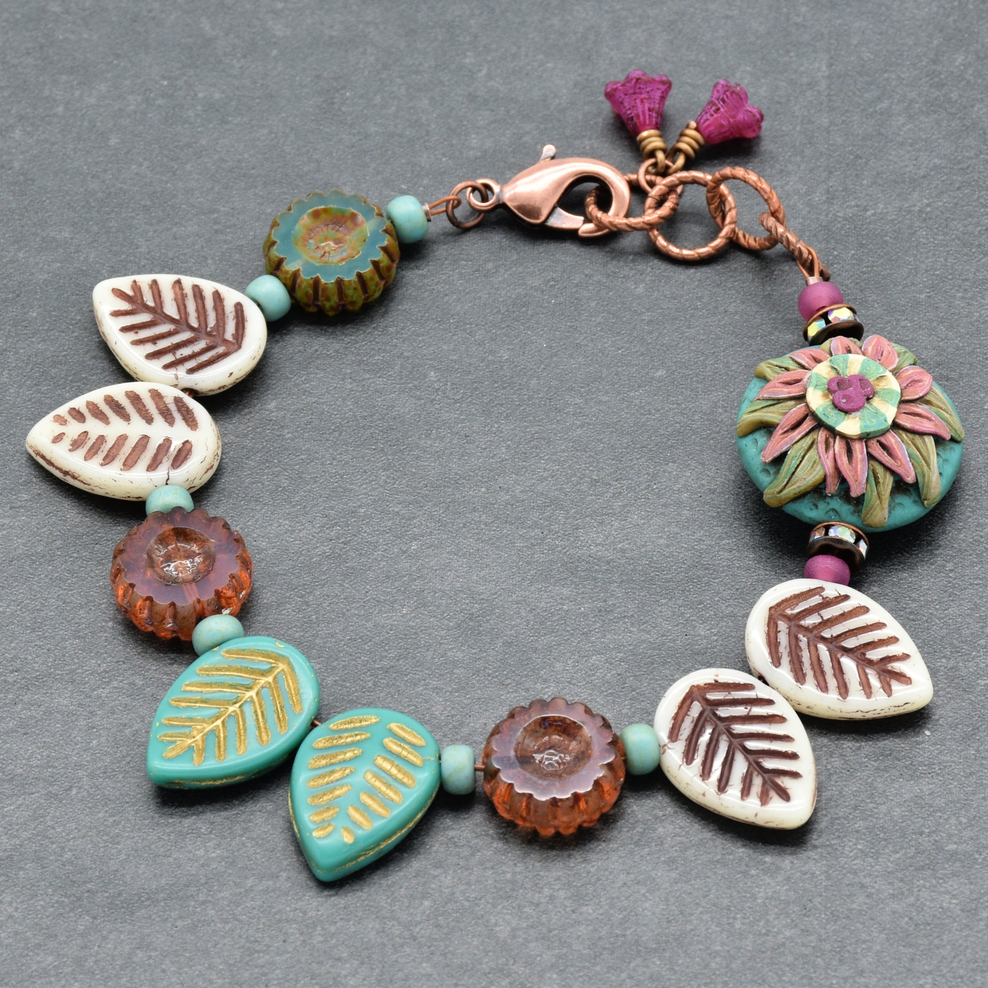 Colorful beaded bracelet with leaf and floral designs on a gray background