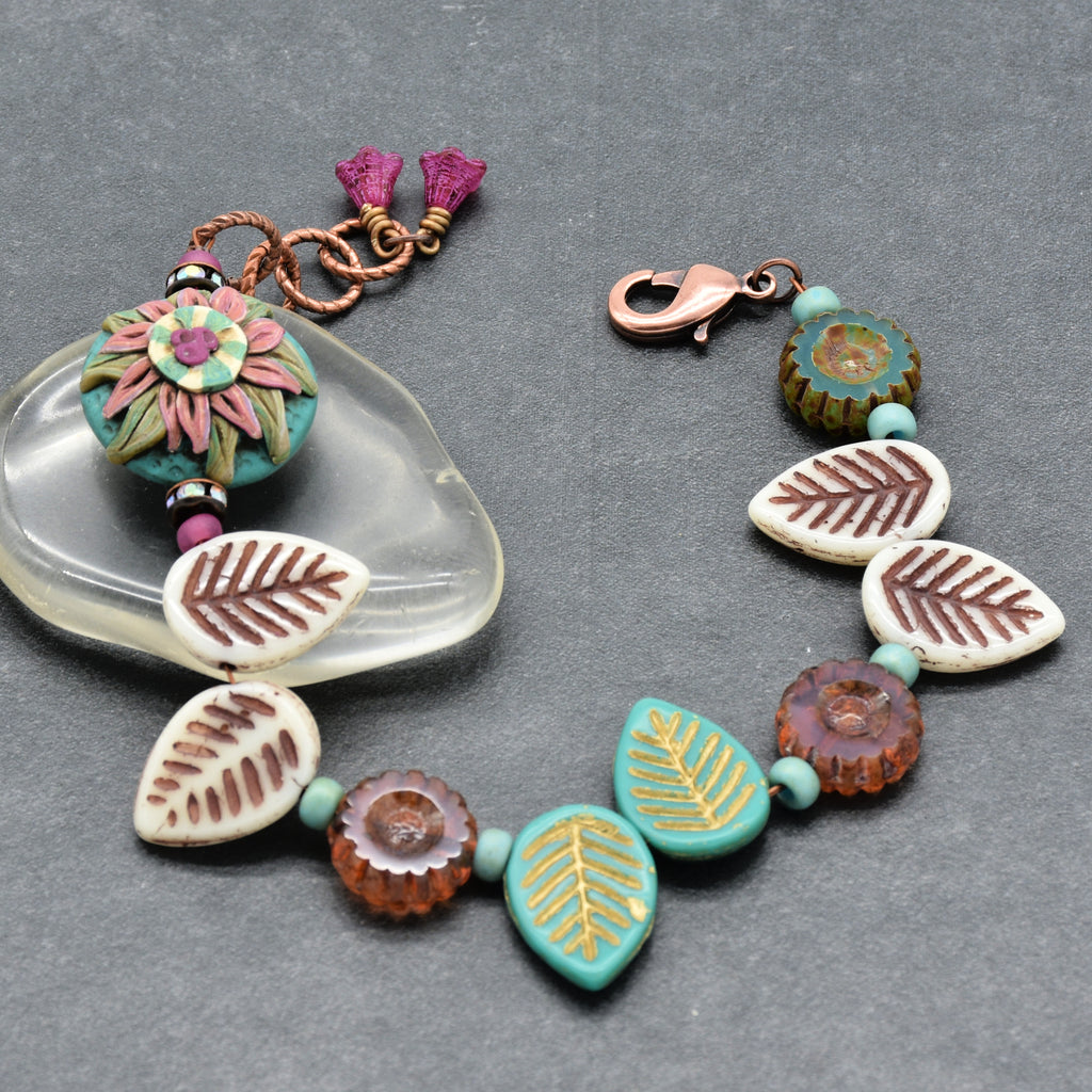 Colorful beaded bracelet with leaf patterns on a gray background