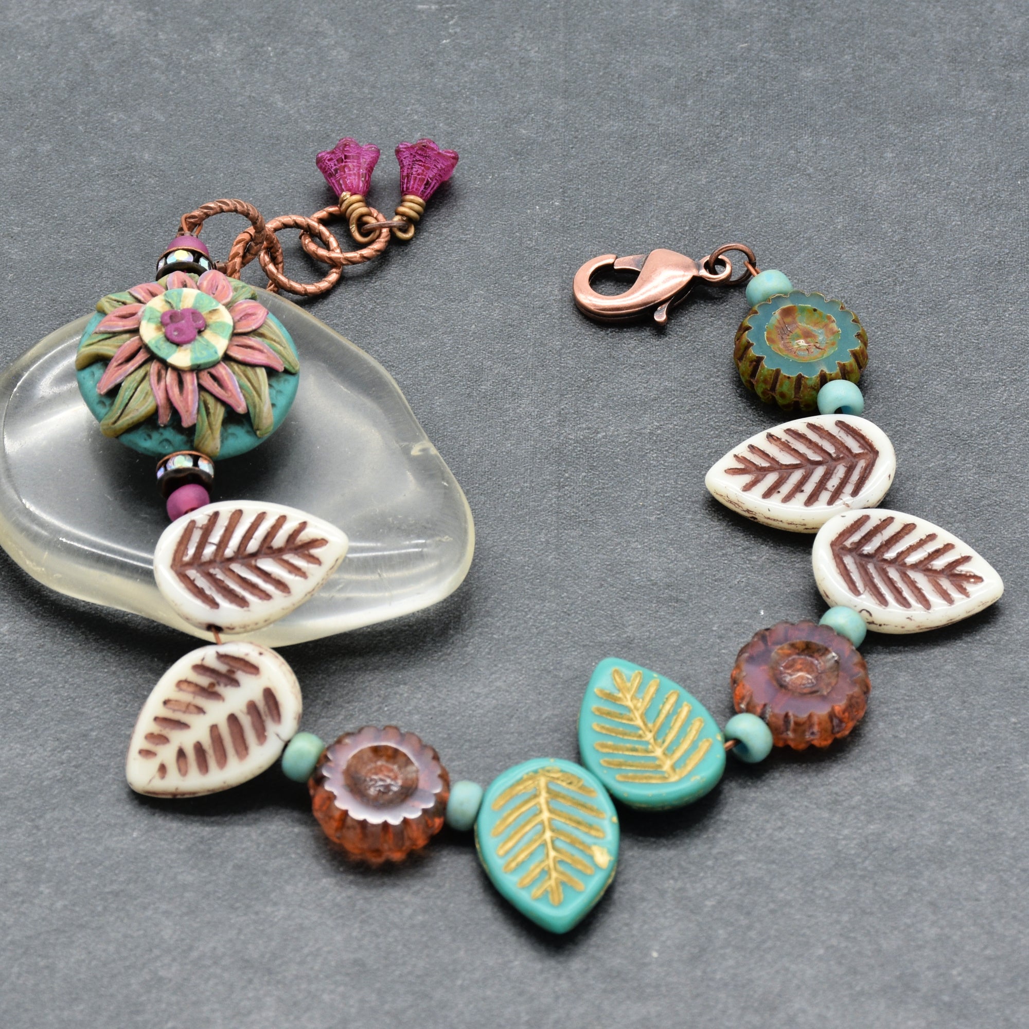 Colorful beaded bracelet with leaf patterns on a gray background