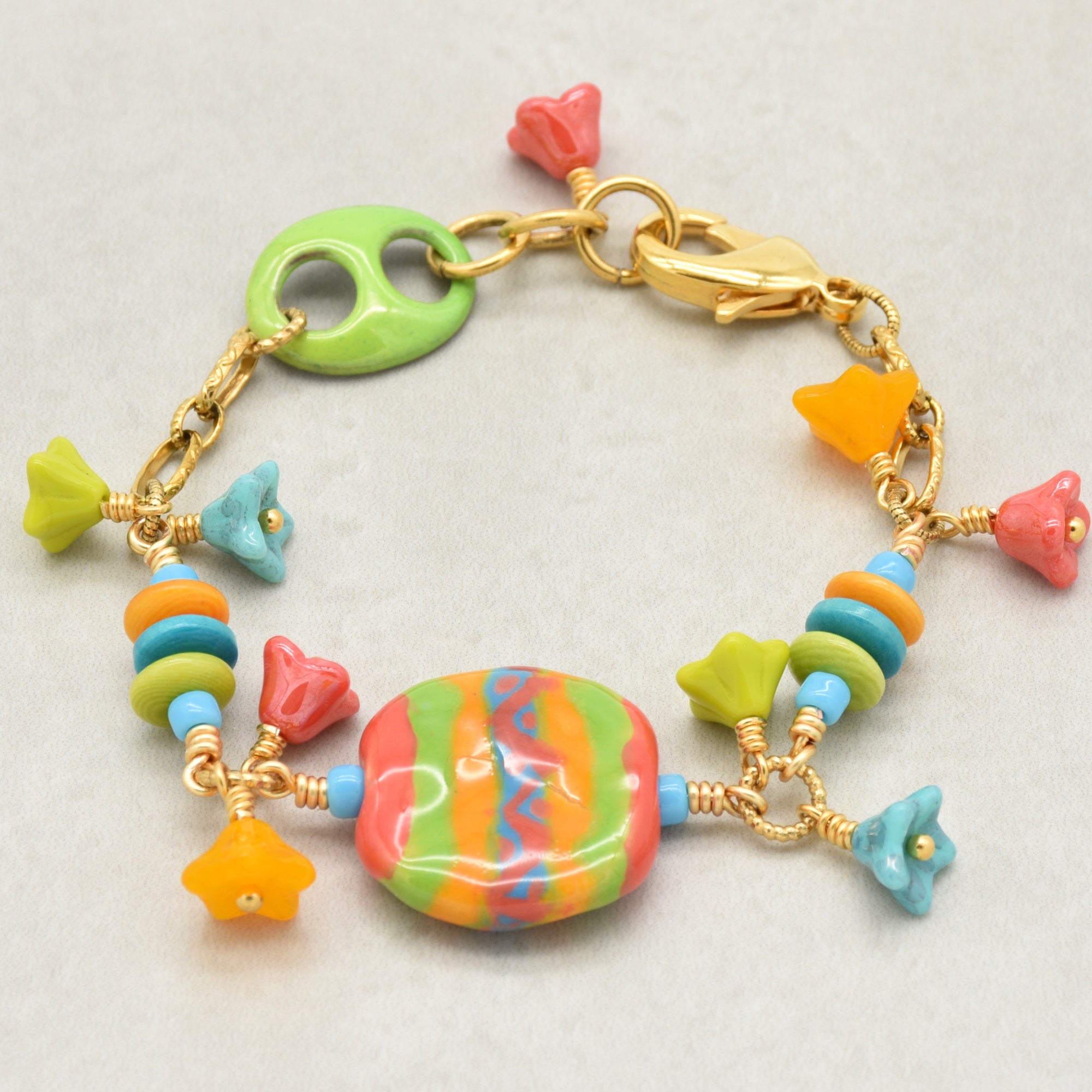 Happy colorful bracelet with African Kazuri focal, tagua nuts, and Czech glass flowers in tangerine, lime, marigold and turquoise on a light surface - handmade with love by Ruby Acorn