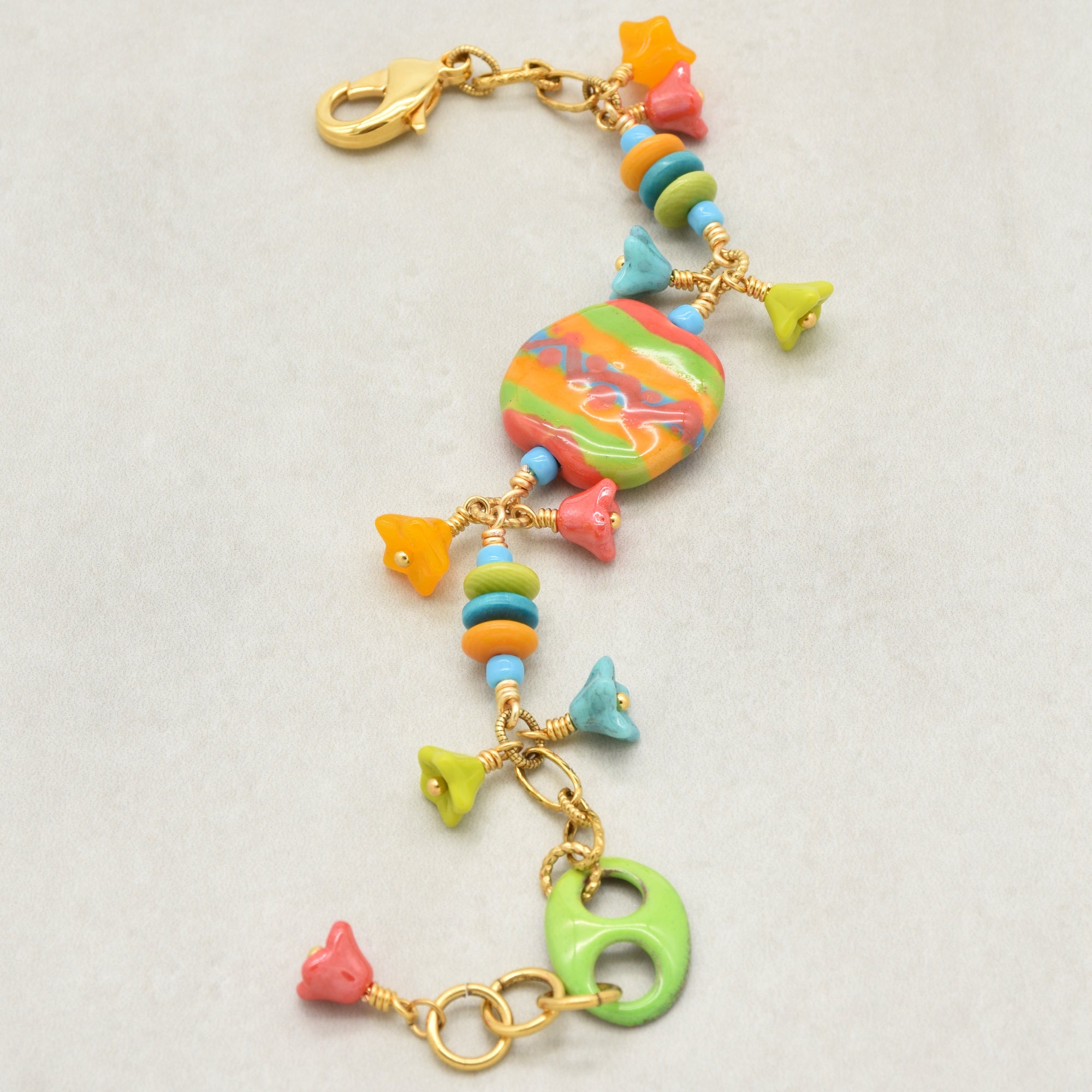 Happy colorful bracelet with African Kazuri focal, tagua nuts, and Czech glass flowers in tangerine, lime, marigold and turquoise on a light surface - handmade with love by Ruby Acorn