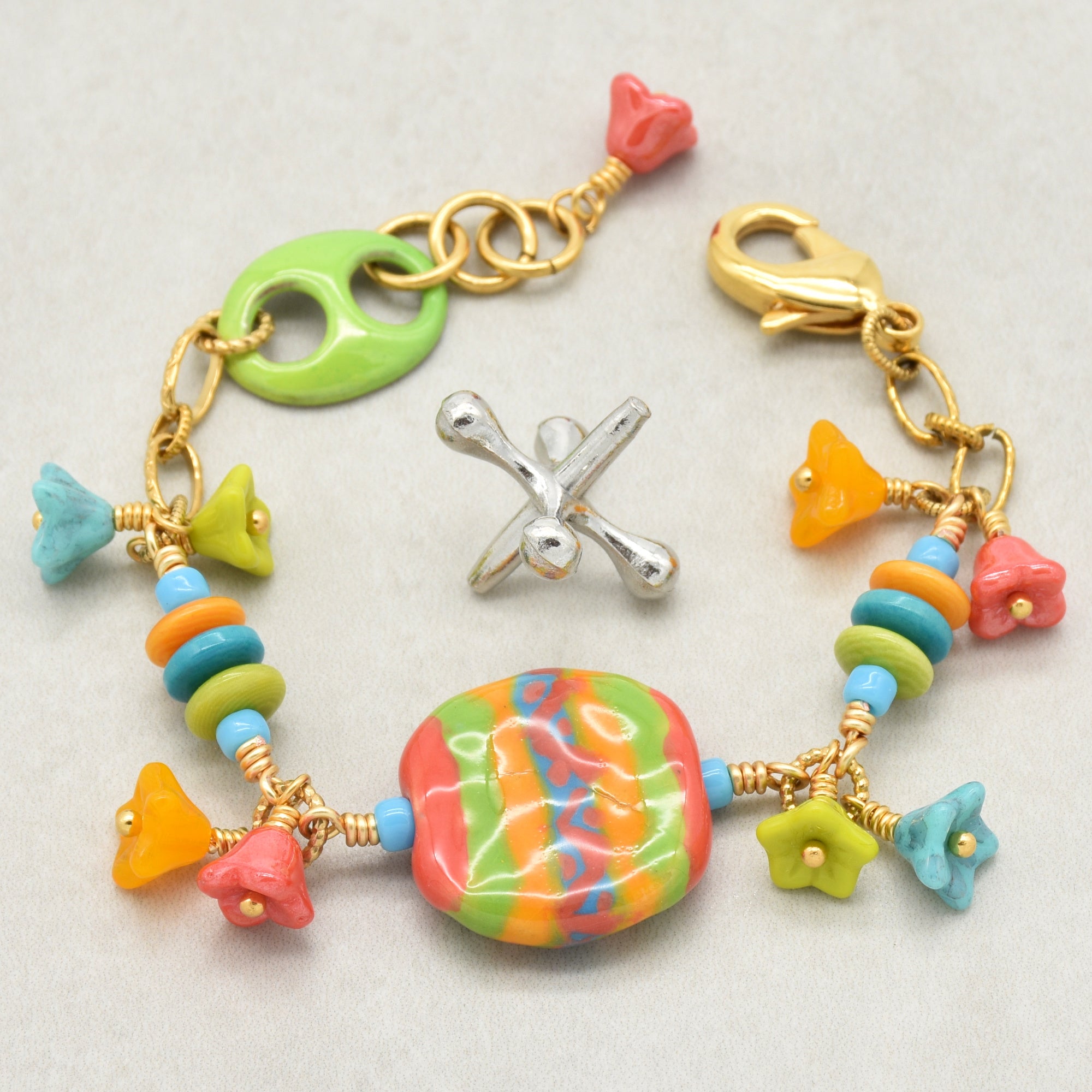 Happy colorful bracelet with African Kazuri focal, tagua nuts, and Czech glass flowers in tangerine, lime, marigold and turquoise on a light surface - handmade with love by Ruby Acorn