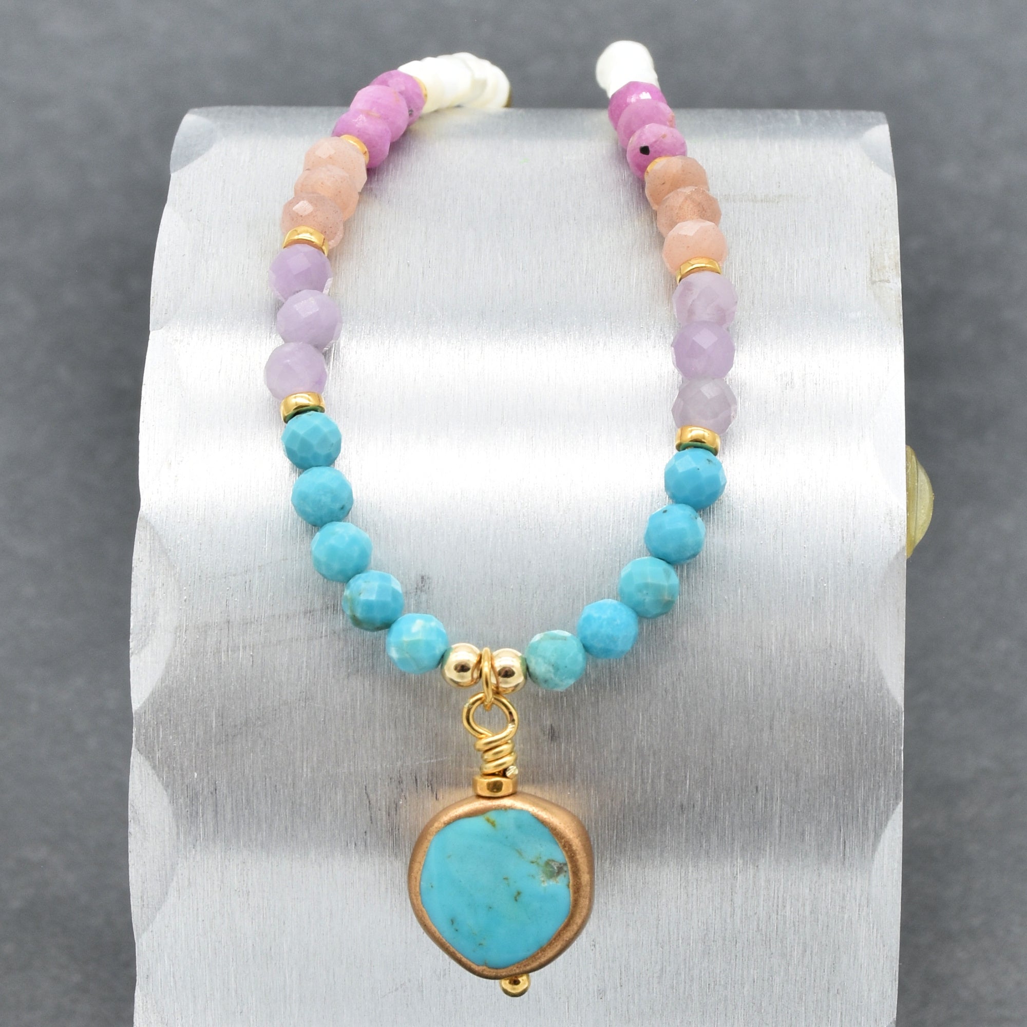Closeup of multi gem gold chain choker necklace with genuine turquoise focal, kunzite, peach moonstone, and more on a silver background - made with love by Ruby Acorn