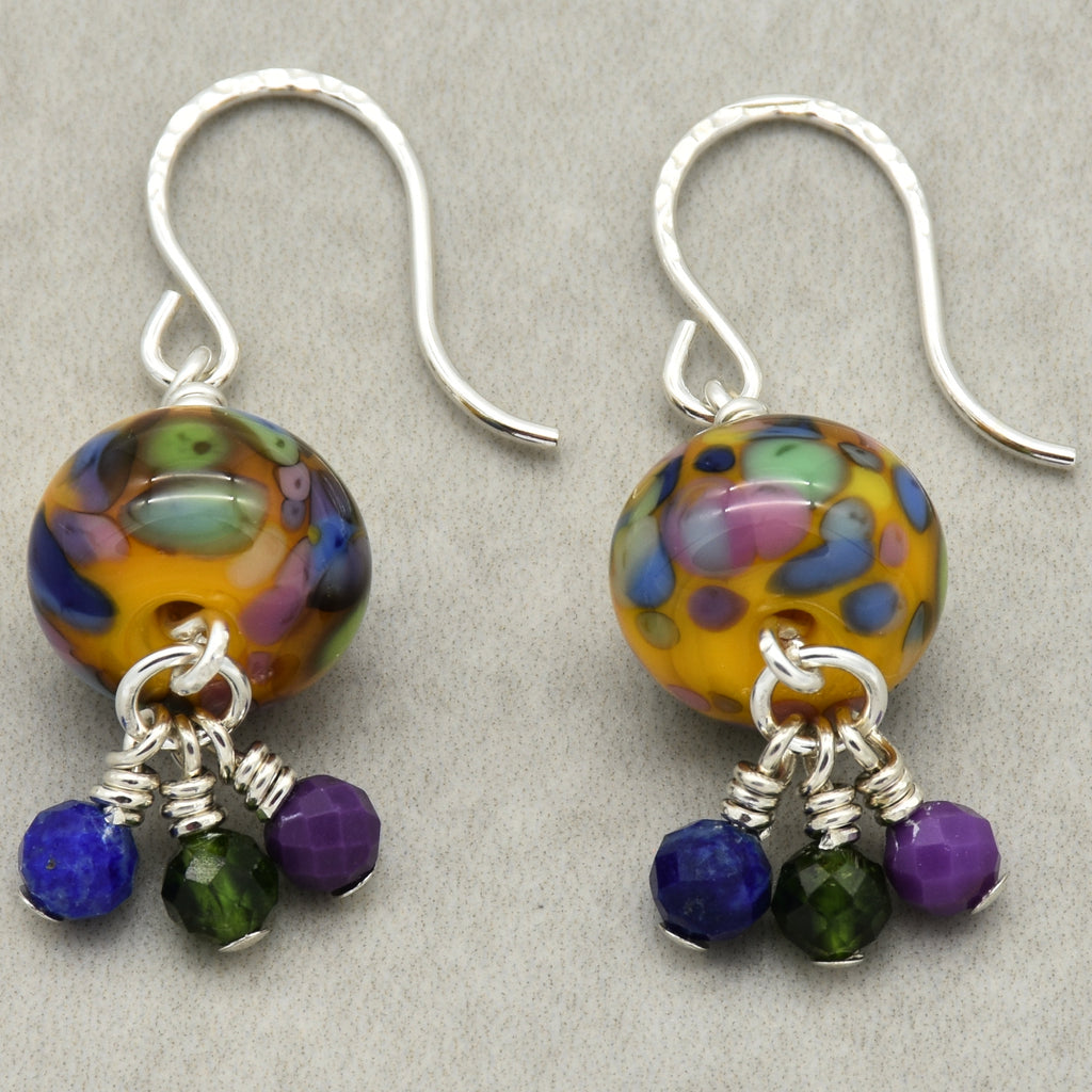 Pair of colorful beaded earrings with silver hooks on a gray background