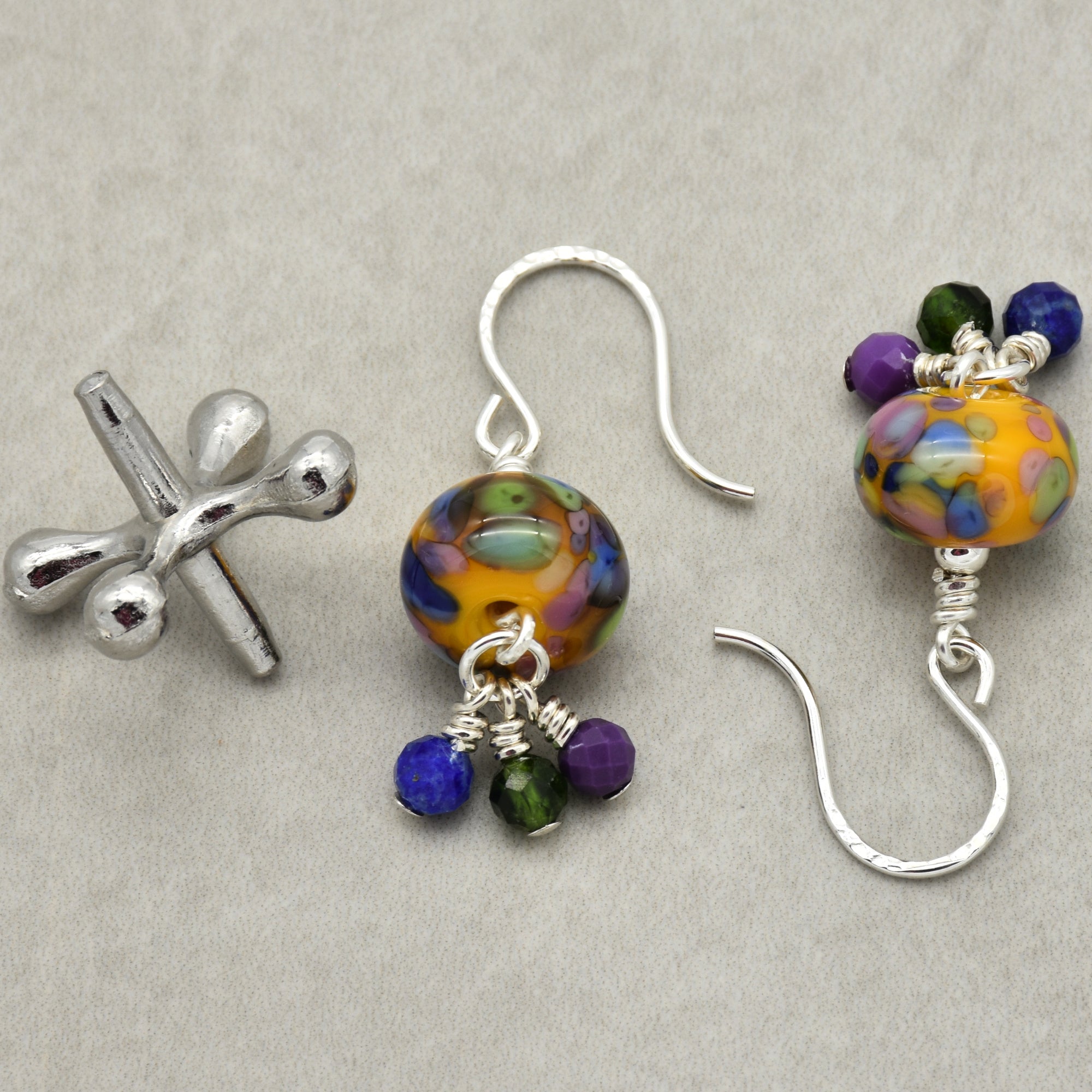 Colorful beaded earrings with silver hooks on a gray background