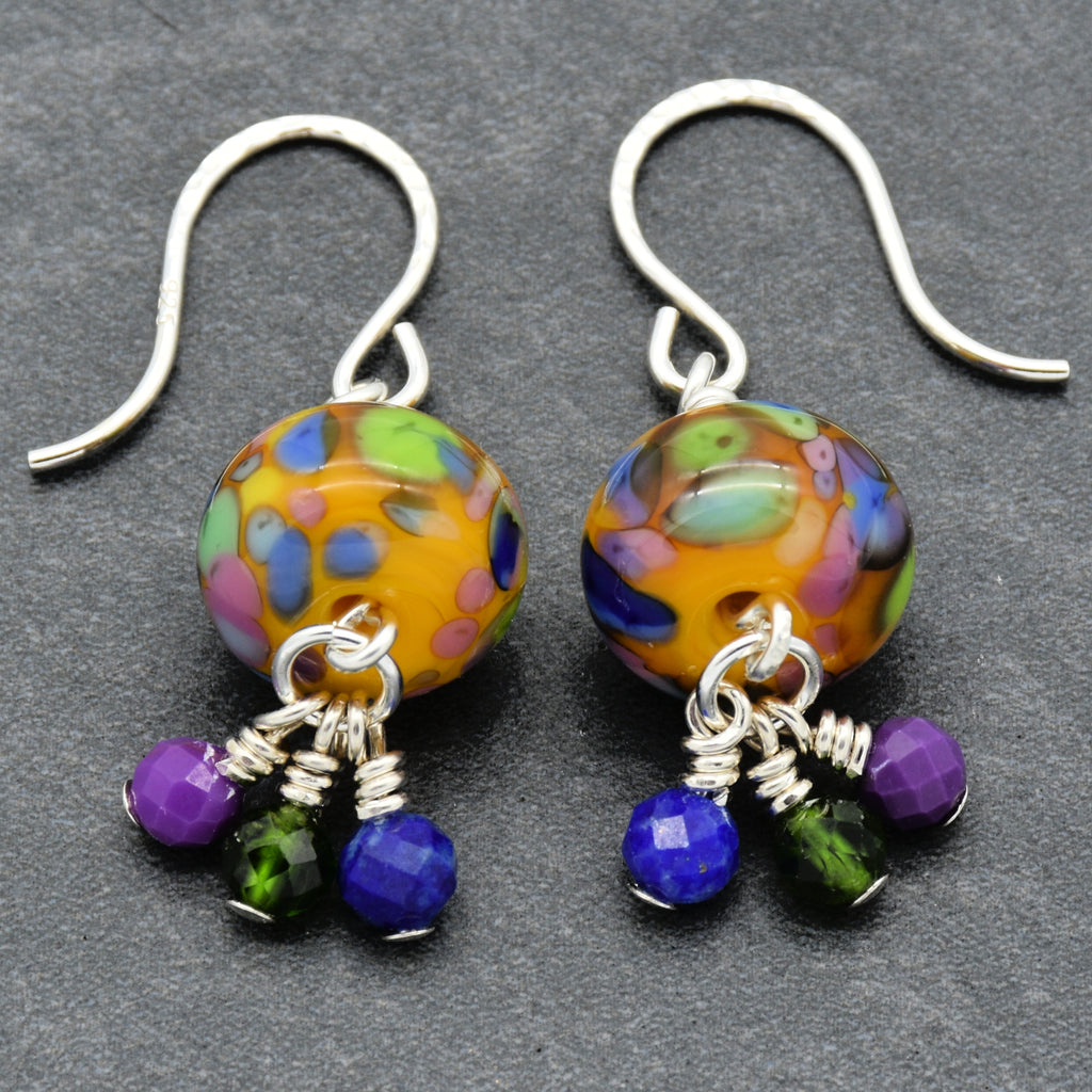 Colorful beaded earrings with silver hooks on a gray background