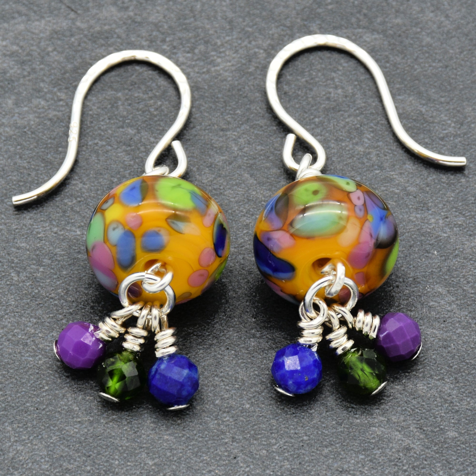Colorful beaded earrings with silver hooks on a gray background