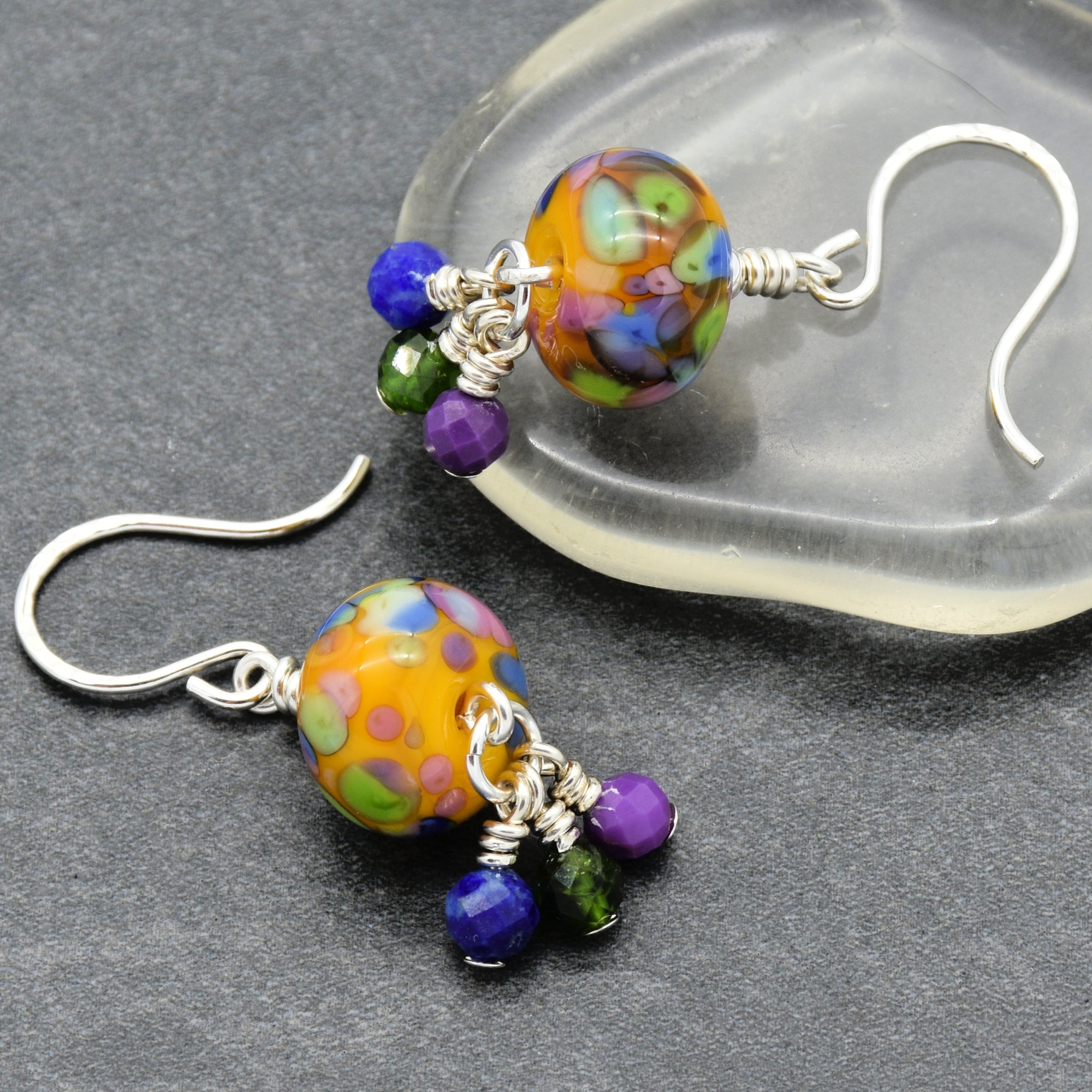 Colorful beaded earrings on a gray surface