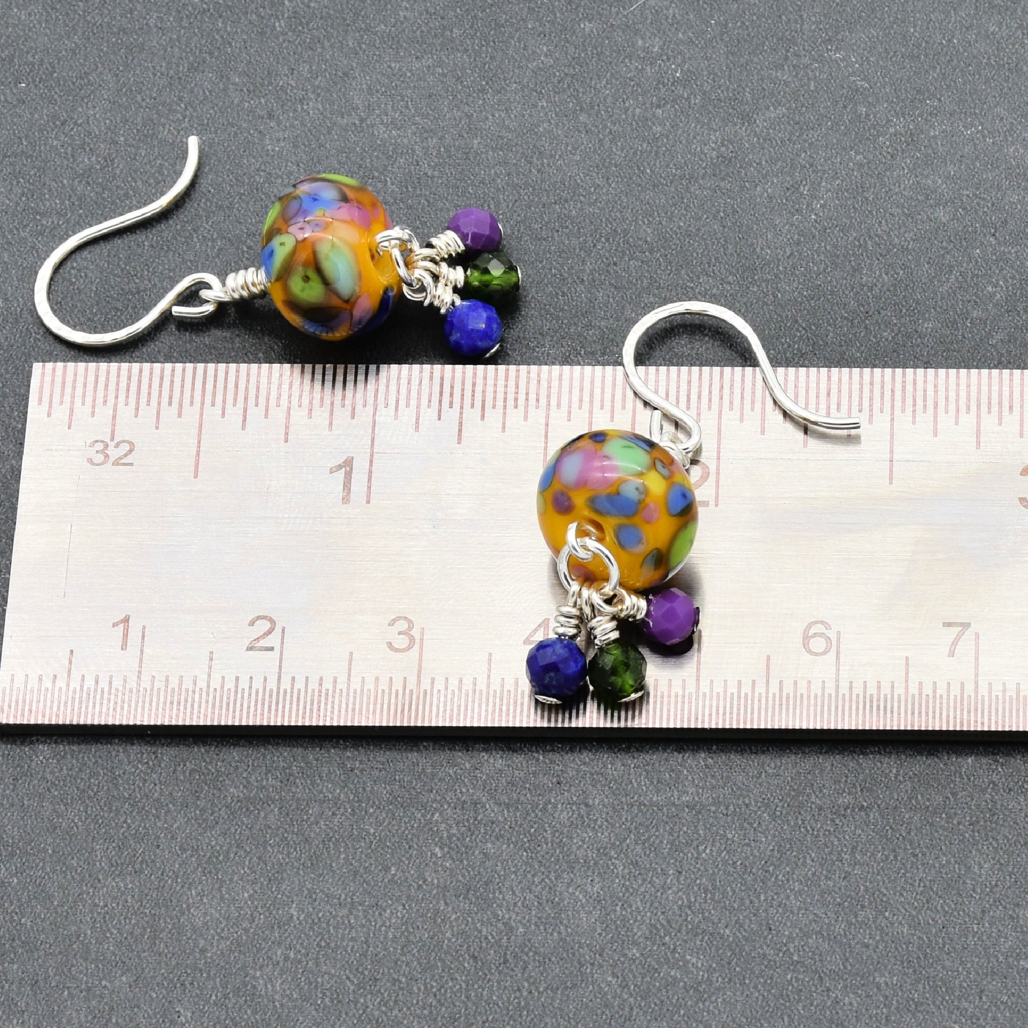 Colorful beaded earrings on a ruler for size reference