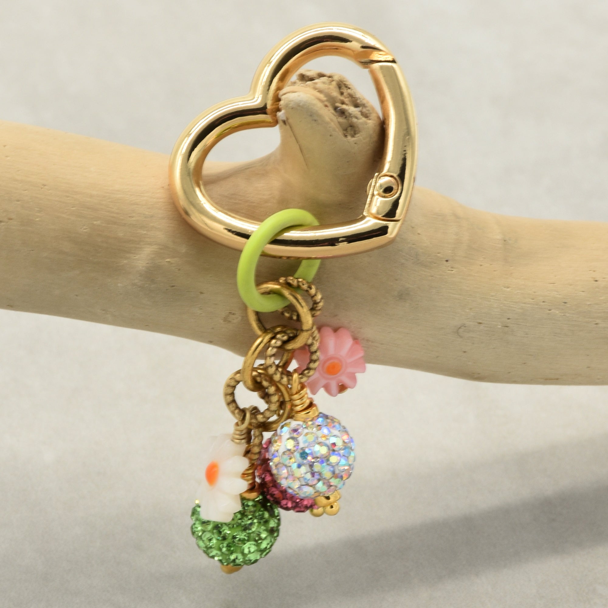 Gold keychain with colorful charms on a wooden branch