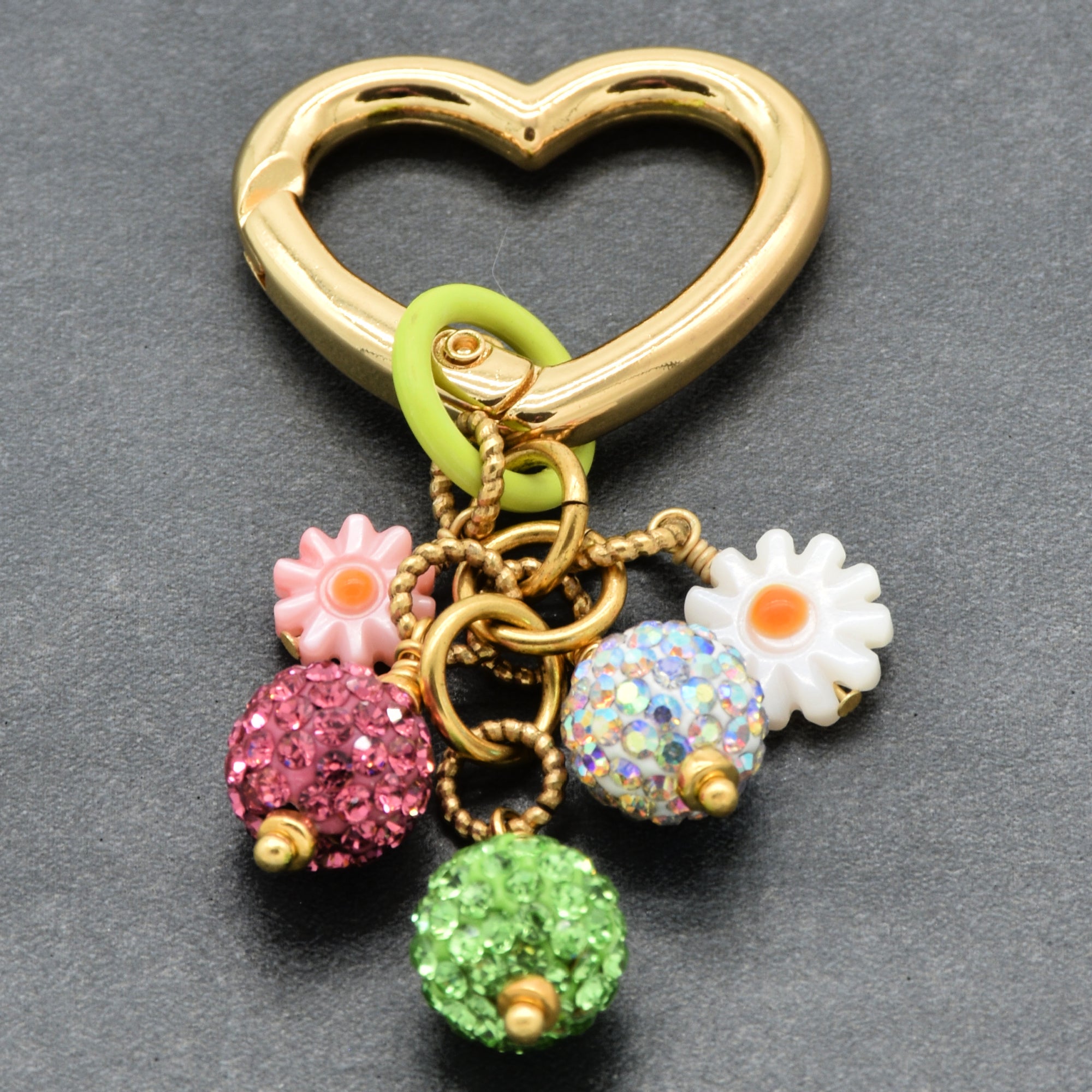Gold heart-shaped keychain with colorful charms on a gray background