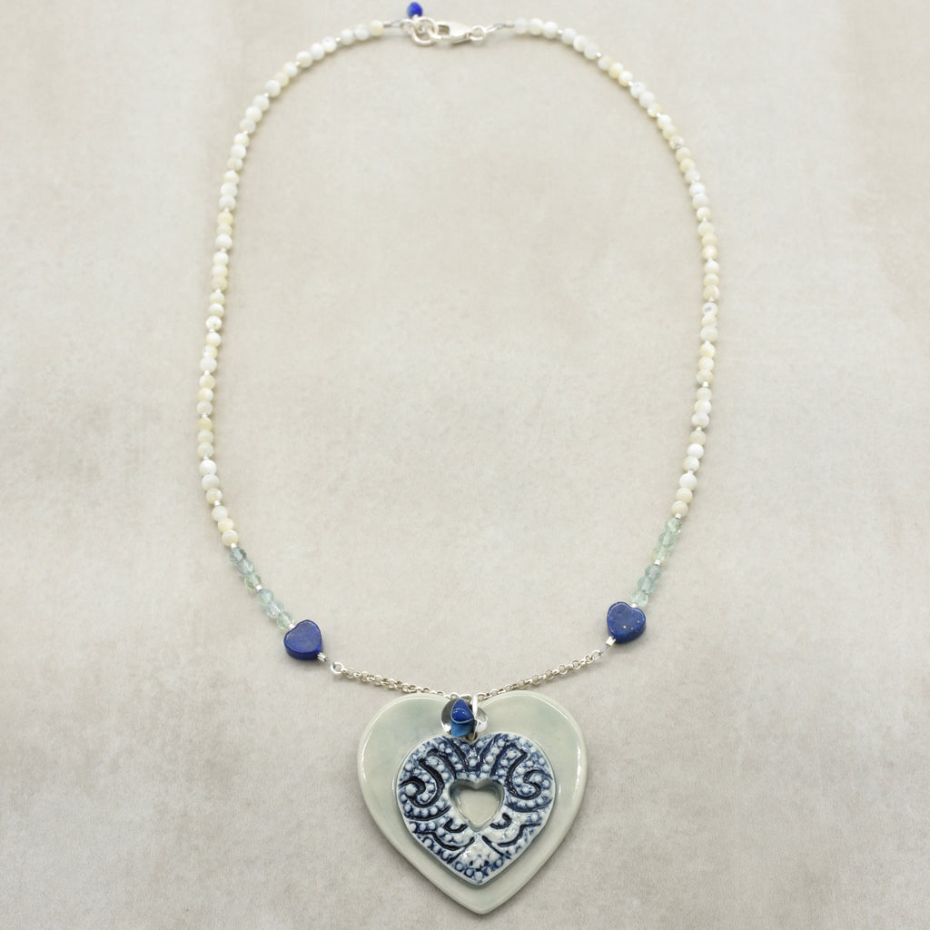 Necklace with heart-shaped pendant and blue beads on a beige background