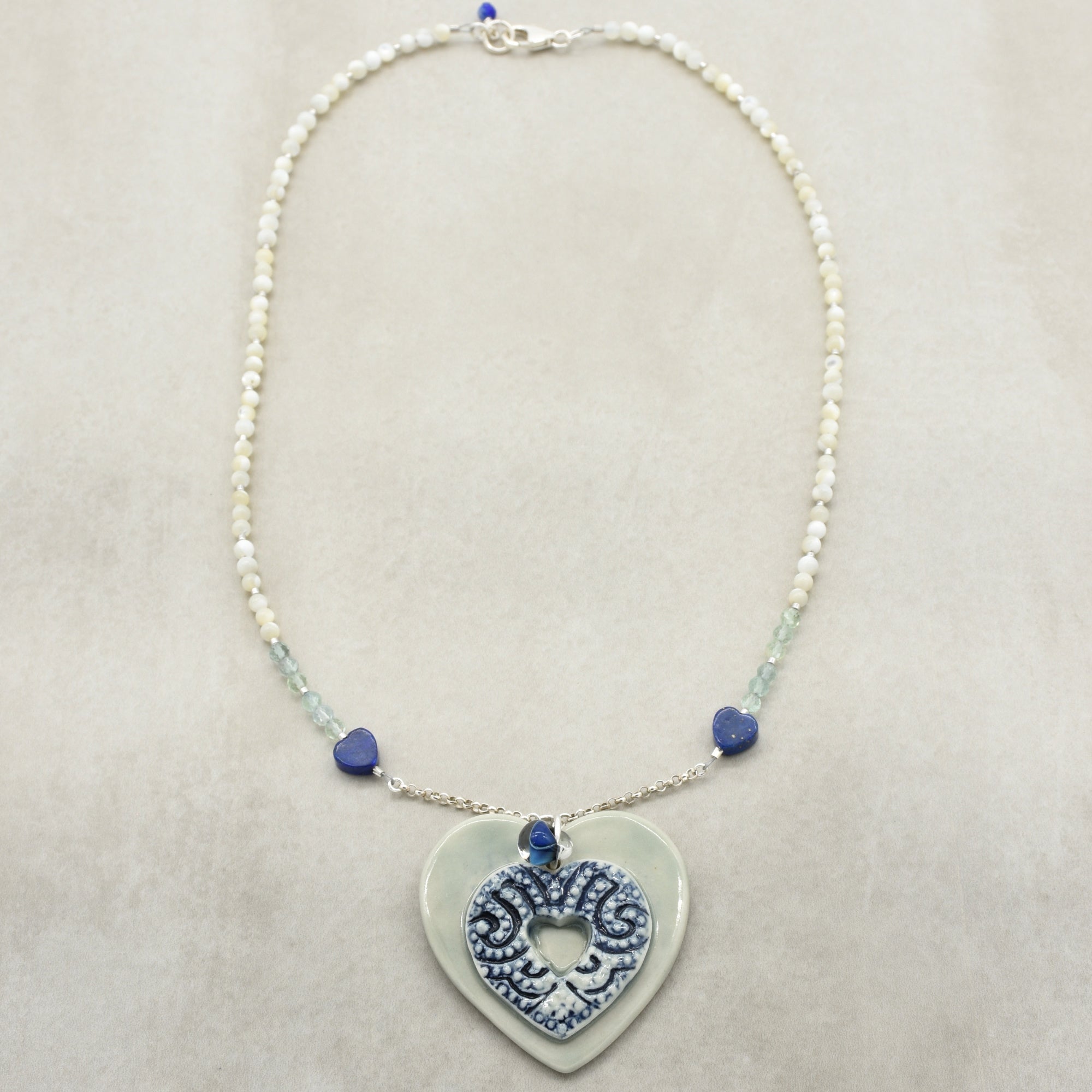 Necklace with heart-shaped pendant and blue beads on a beige background