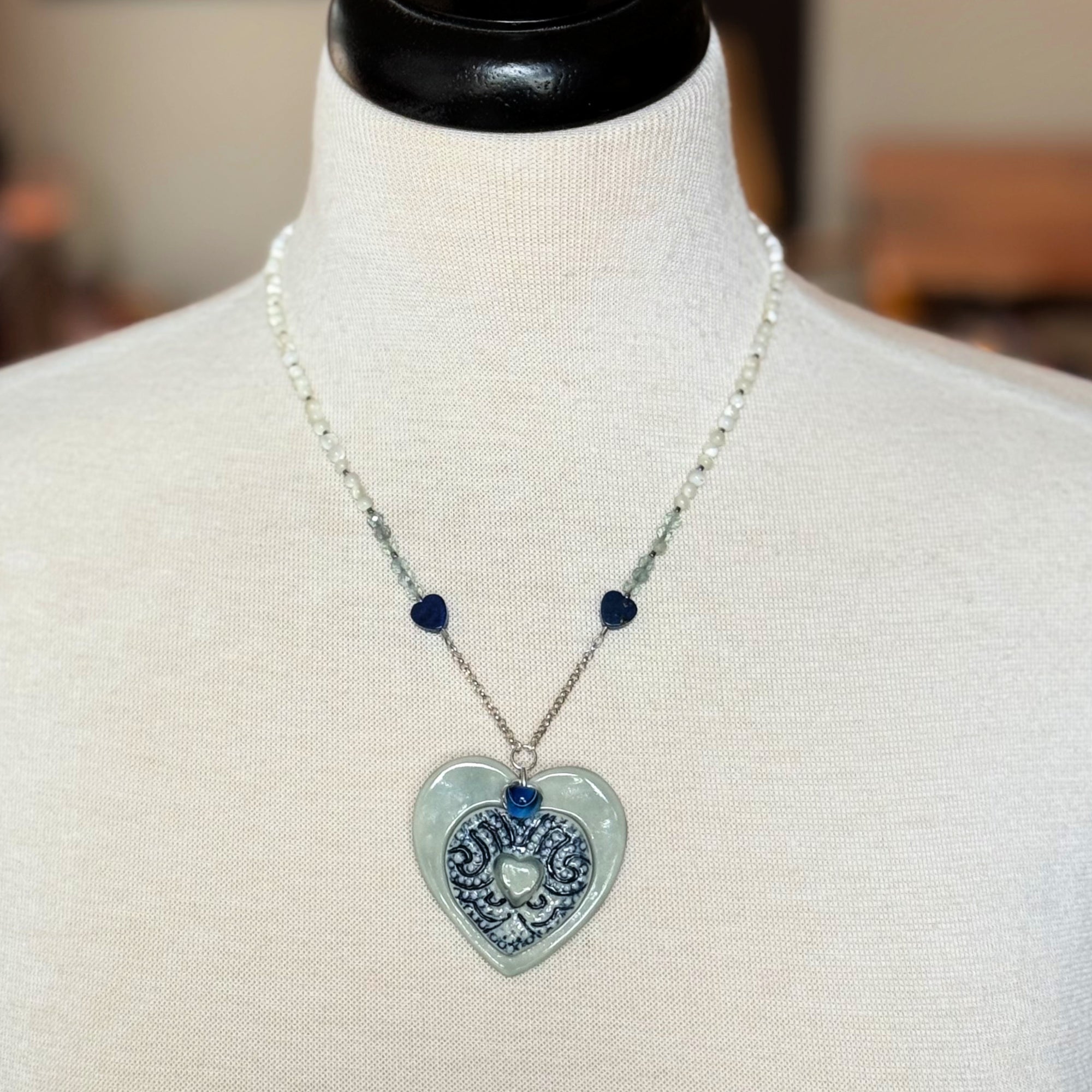 Necklace with a heart-shaped pendant on a mannequin bust.