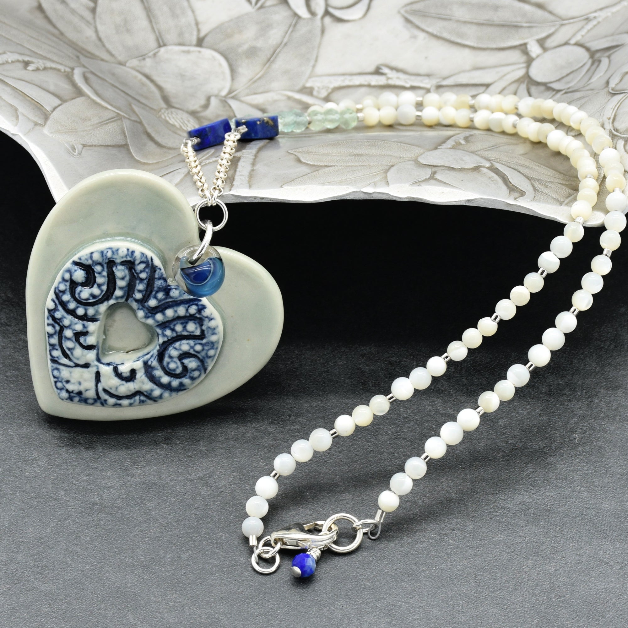 Necklace with heart-shaped pendant and blue accents on a textured surface