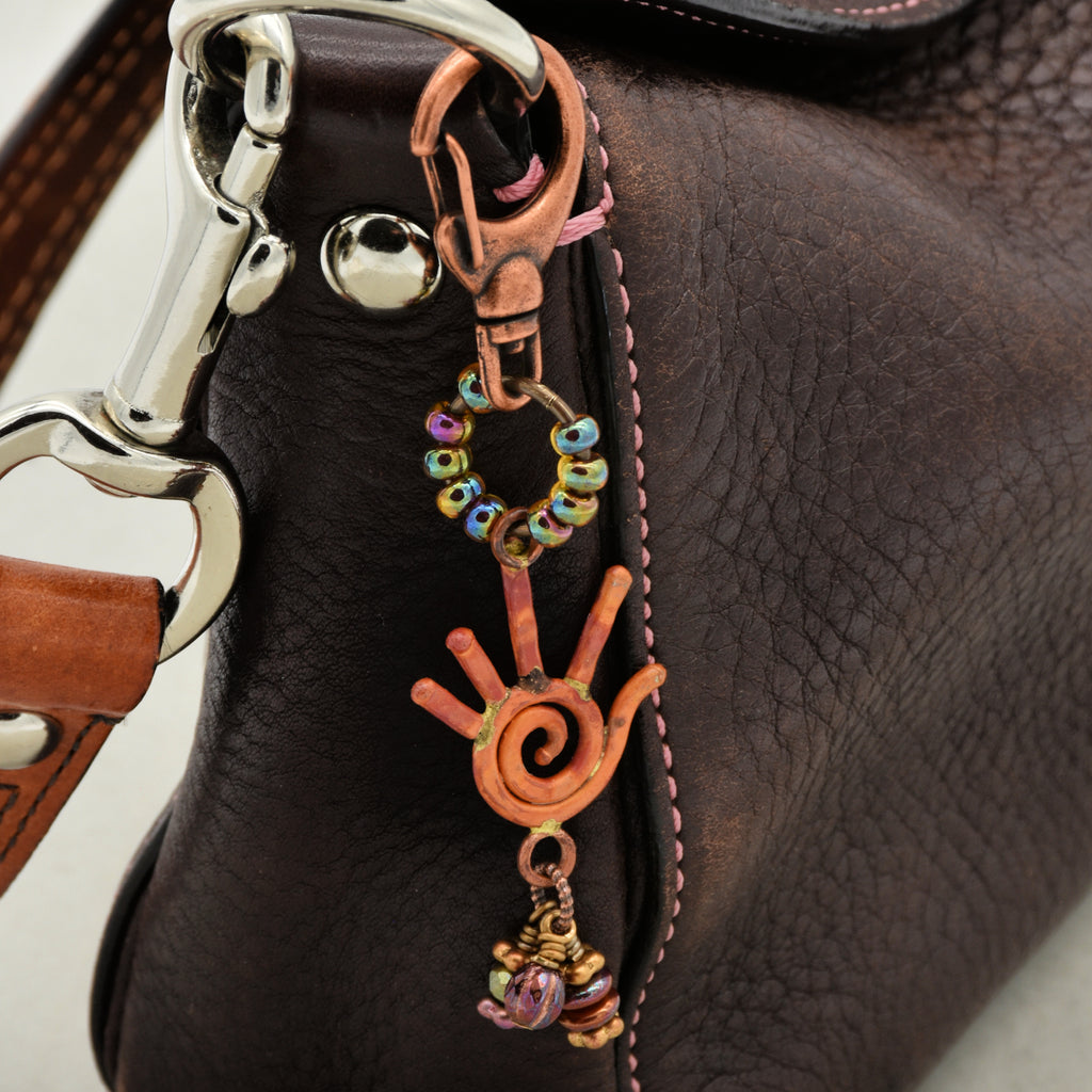 Close-up of a brown leather bag with decorative metal and bead charm.
