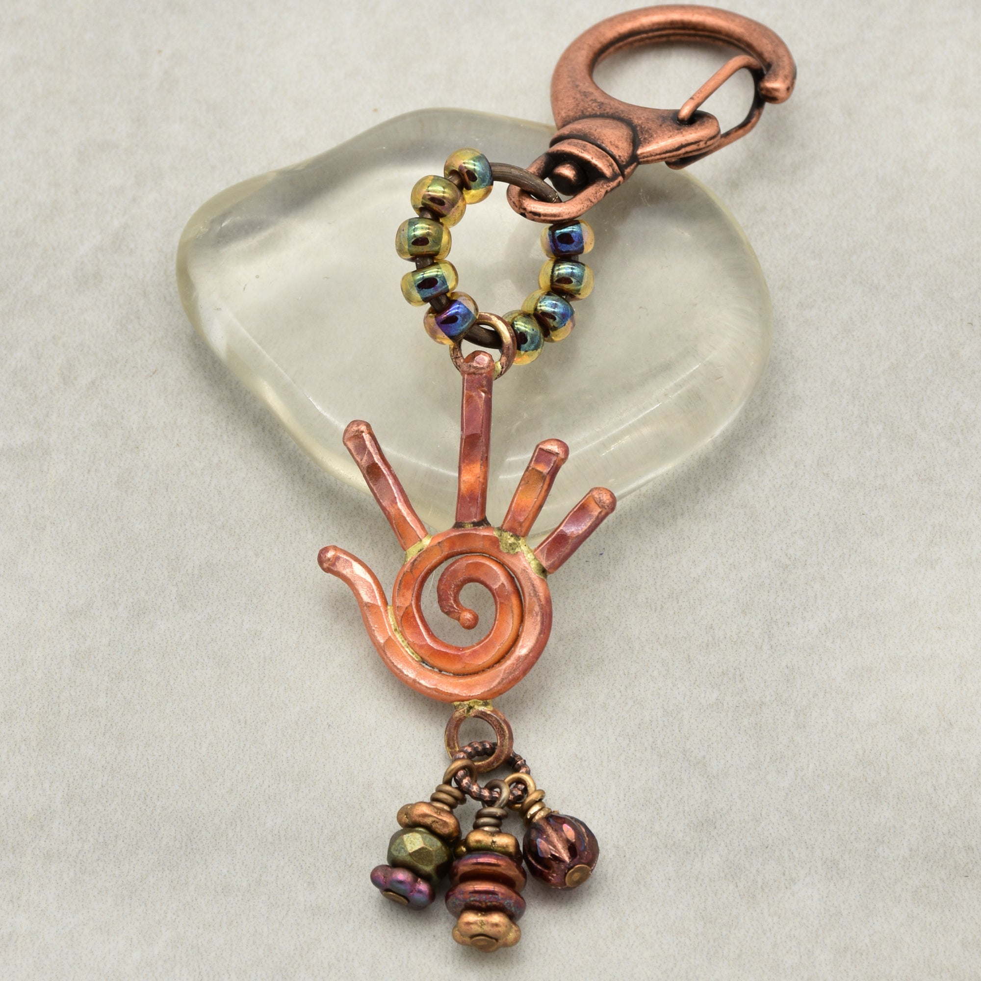 Copper keychain with spiral design and beads on a clear heart-shaped stone