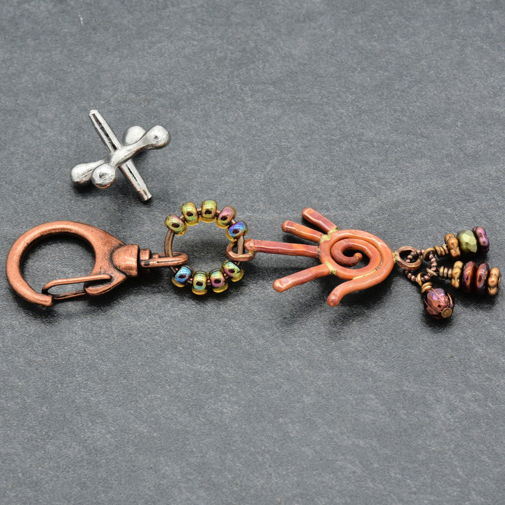 Decorative keychain with metal and bead components on a gray background