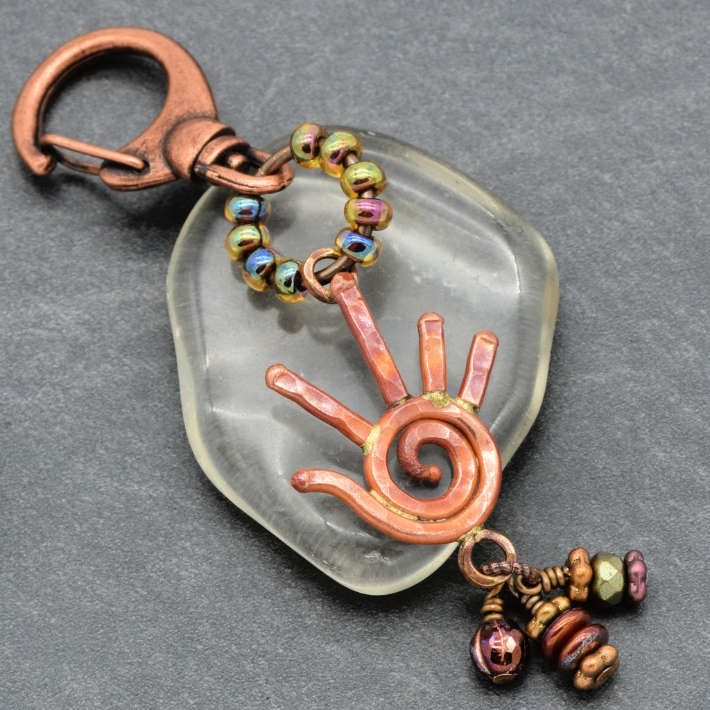 Decorative keychain with spiral design and beads on a gray background