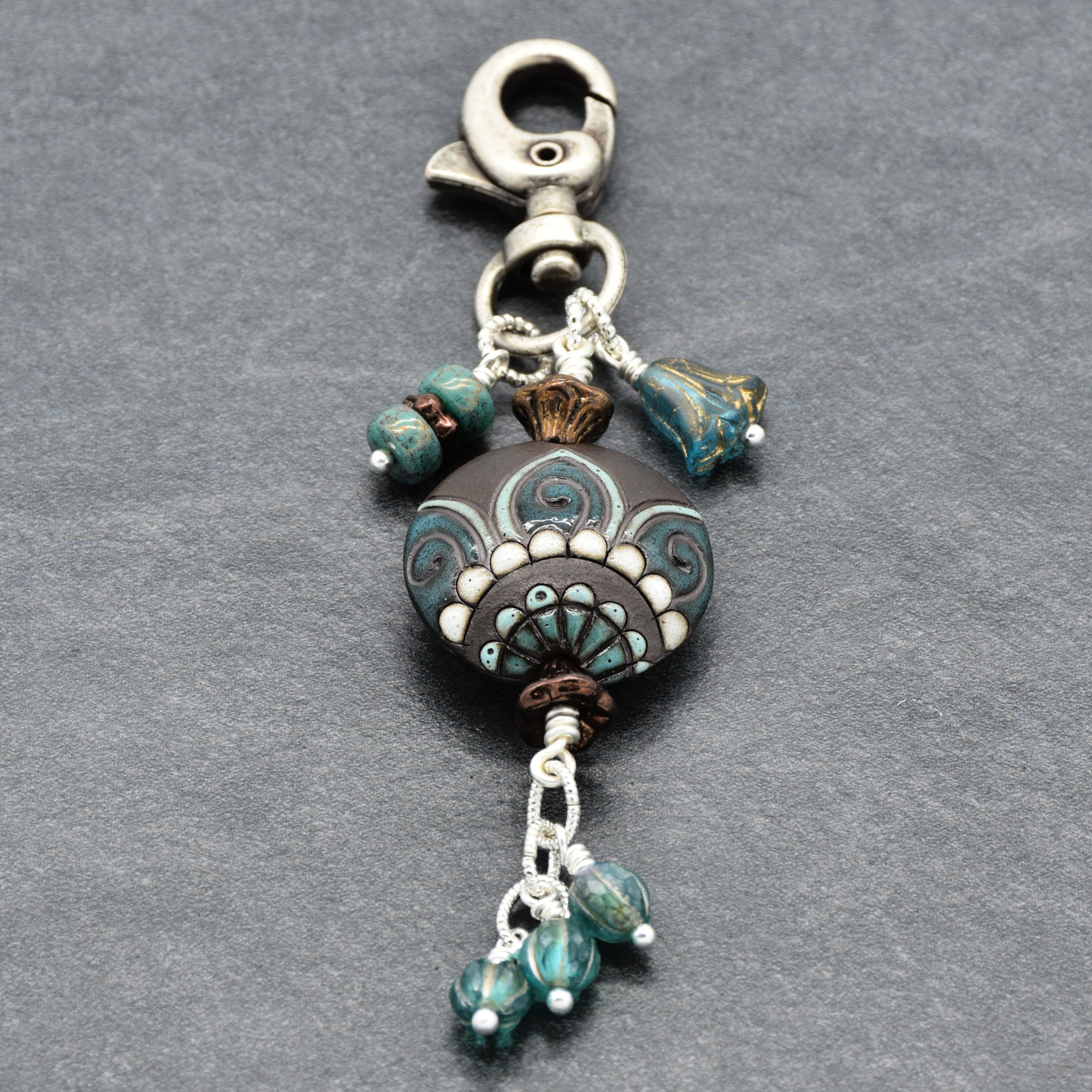 Decorative keychain with beads and clasp on a gray background