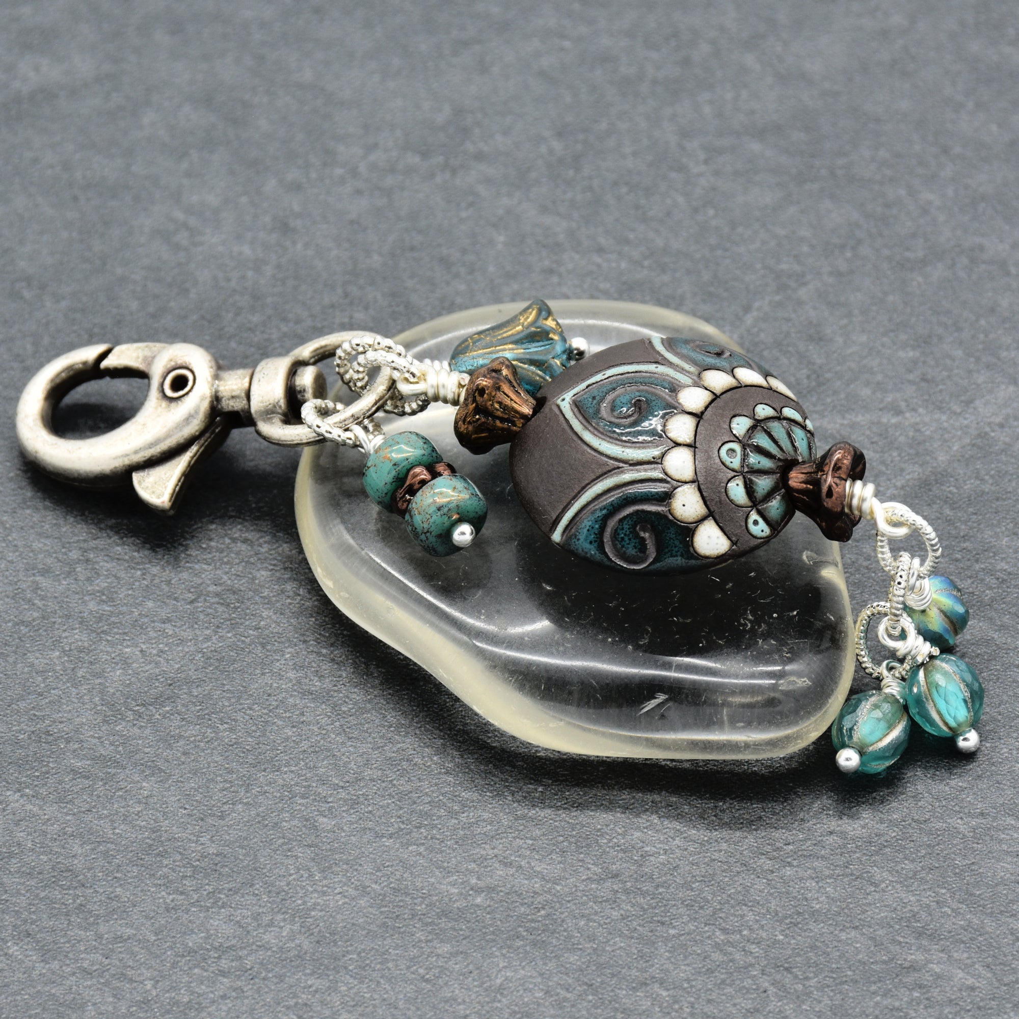 Decorative keychain with beads and clasp on a gray background