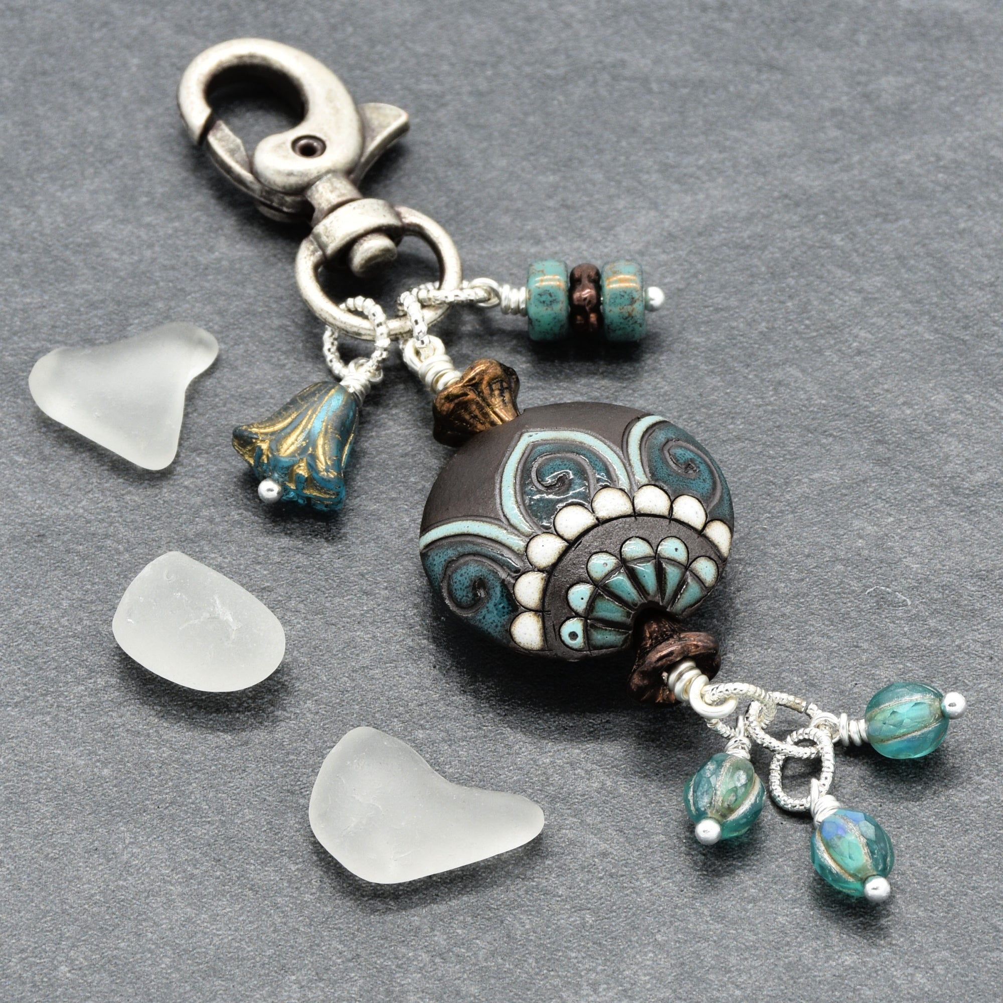 Decorative keychain with beads and charms on a gray background