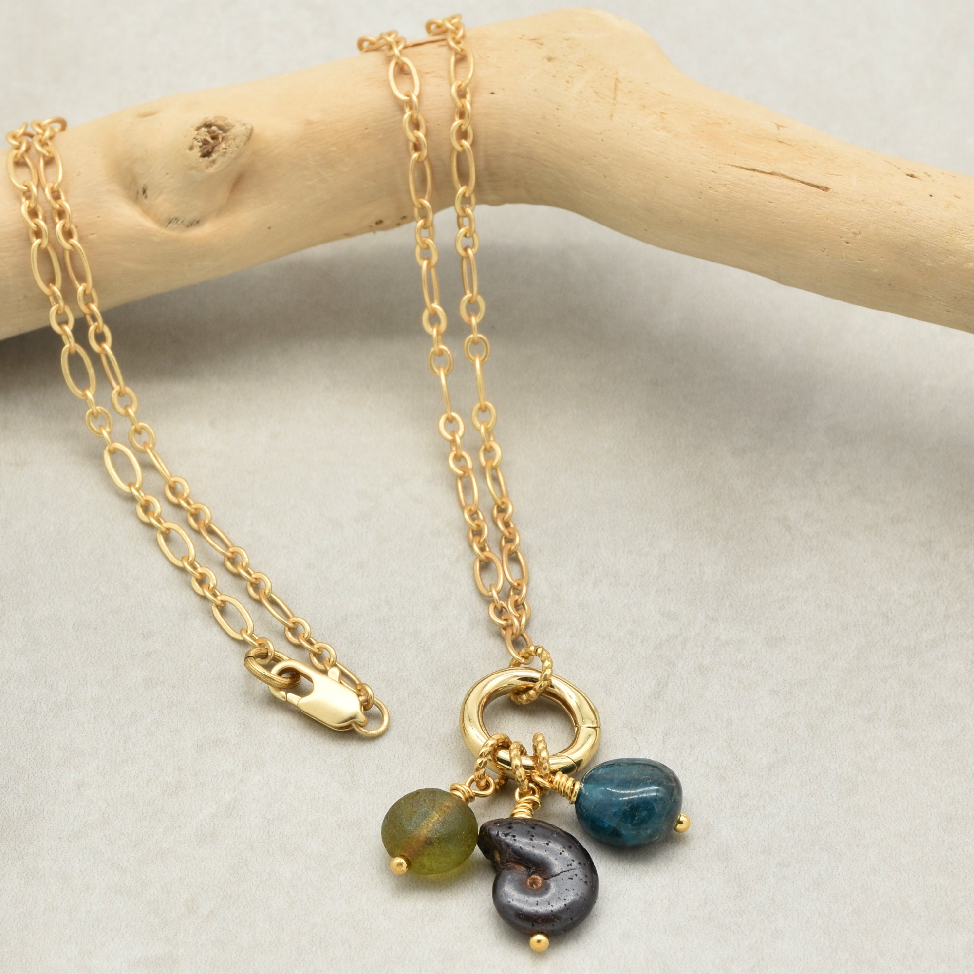 Gold charm necklace with ammonite, apatite and Czech glass on a light background - wearable art by Ruby Acorn