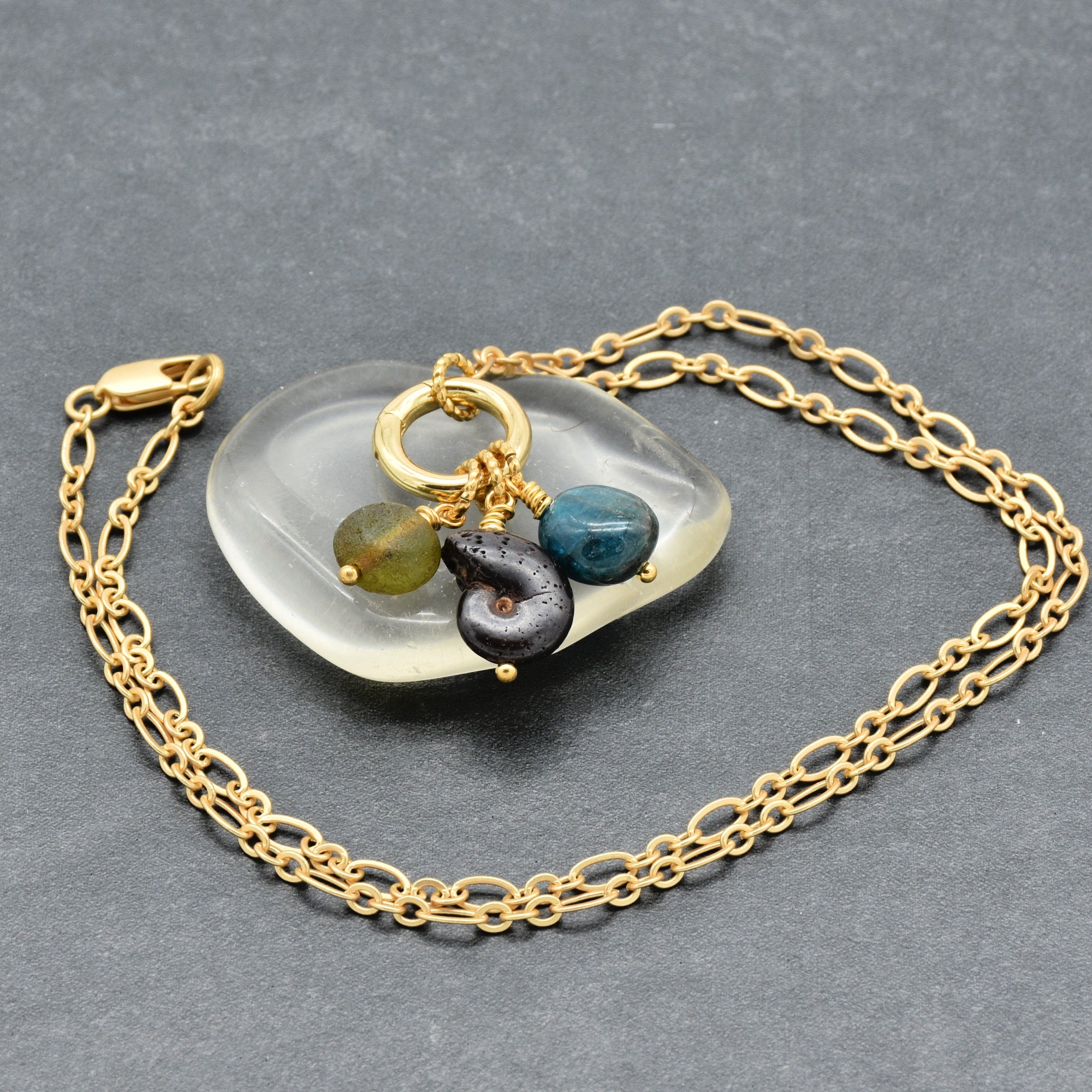 Gold chain charm necklace with natural ammonite fossil, apatite, and Czech glass on a gray background - wearable one of kind art by Ruby Acorn