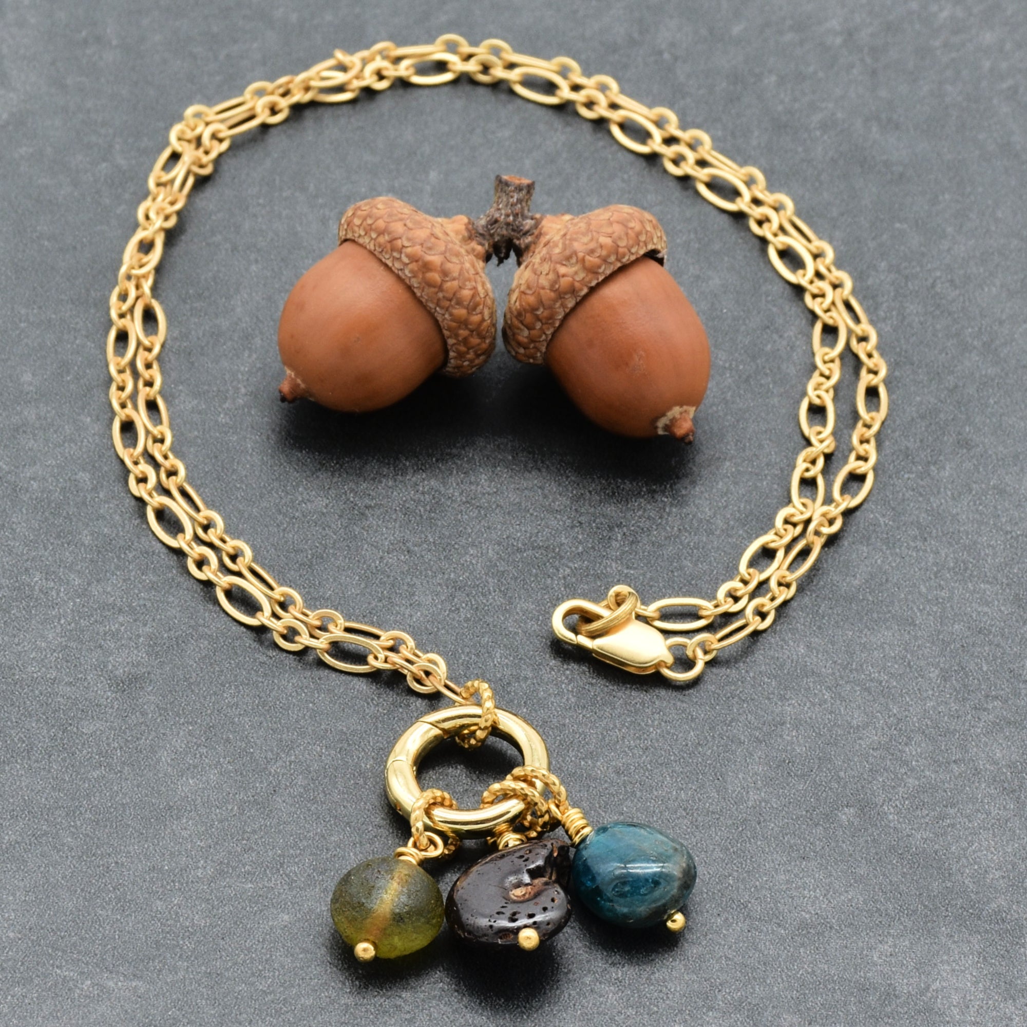 Gold chain charm necklace with brown ammonite, blue apatite and green Czech glass on a dark background - wearable art by Ruby Acorn