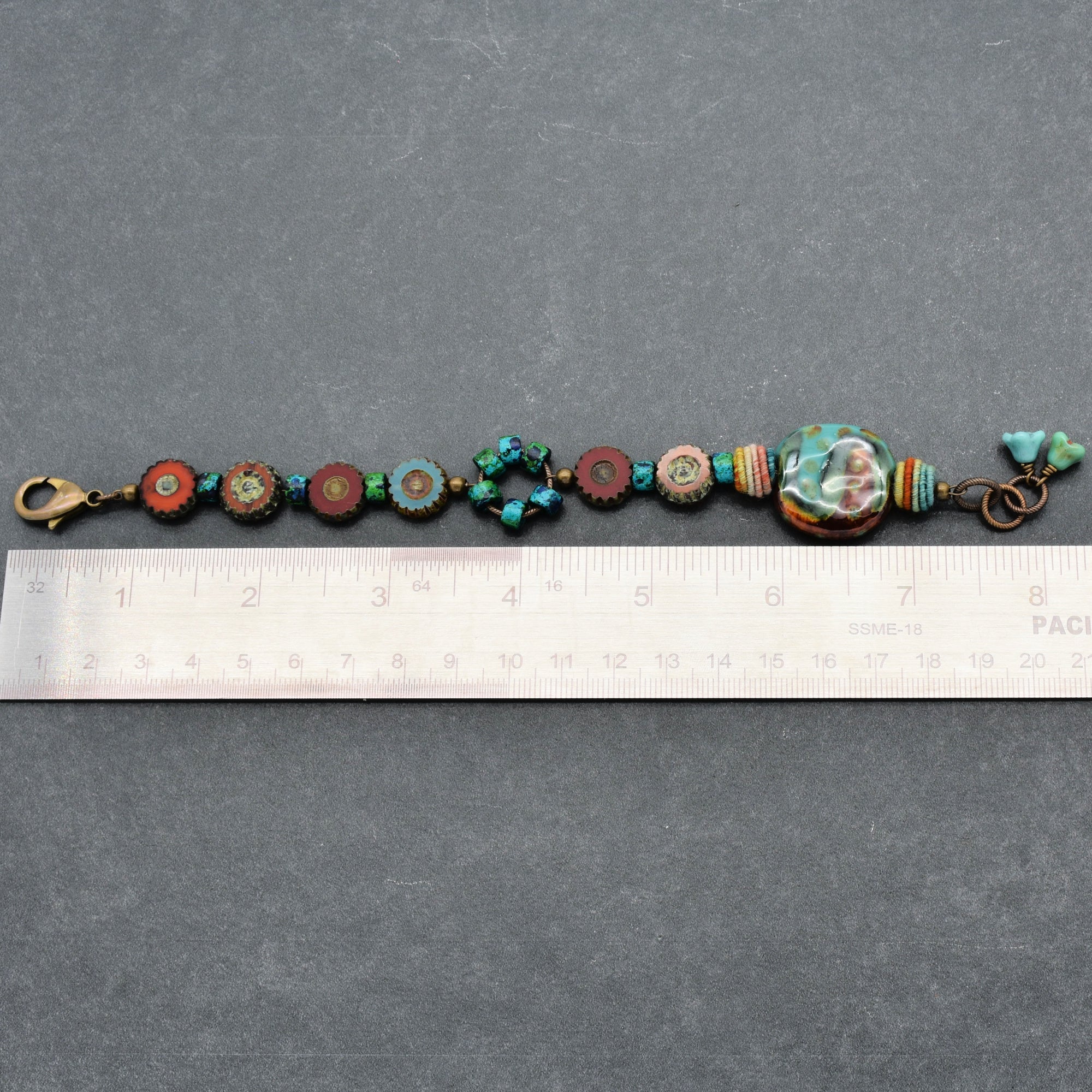 This image shows a bracelet. The size of the jewelry along with the clasp and arrangement of beads clearly indicate that it is designed to be worn around the wrist. The ruler also suggests the length is consistent with that of a bracelet.