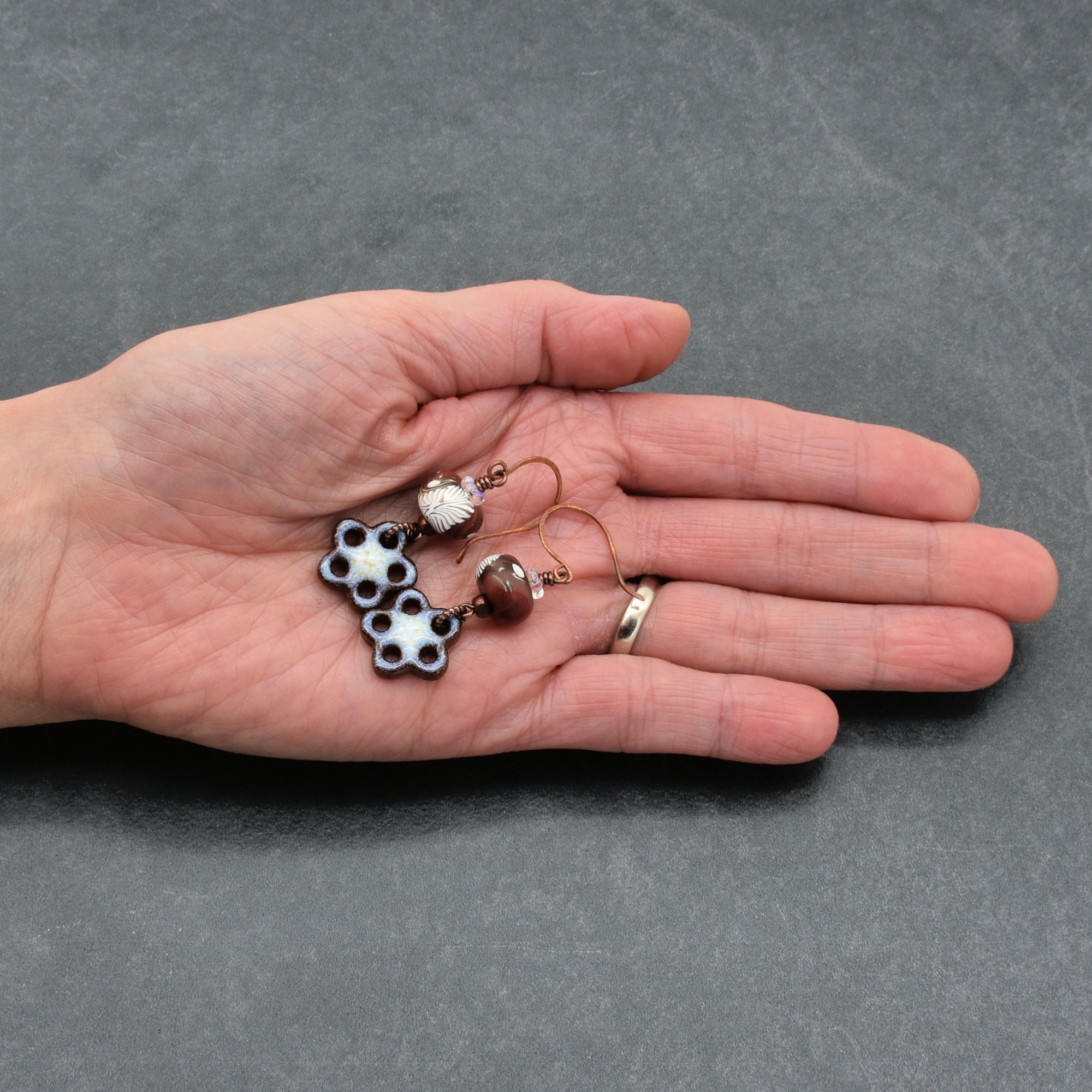 Hand holding a pair of earrings against a gray background
