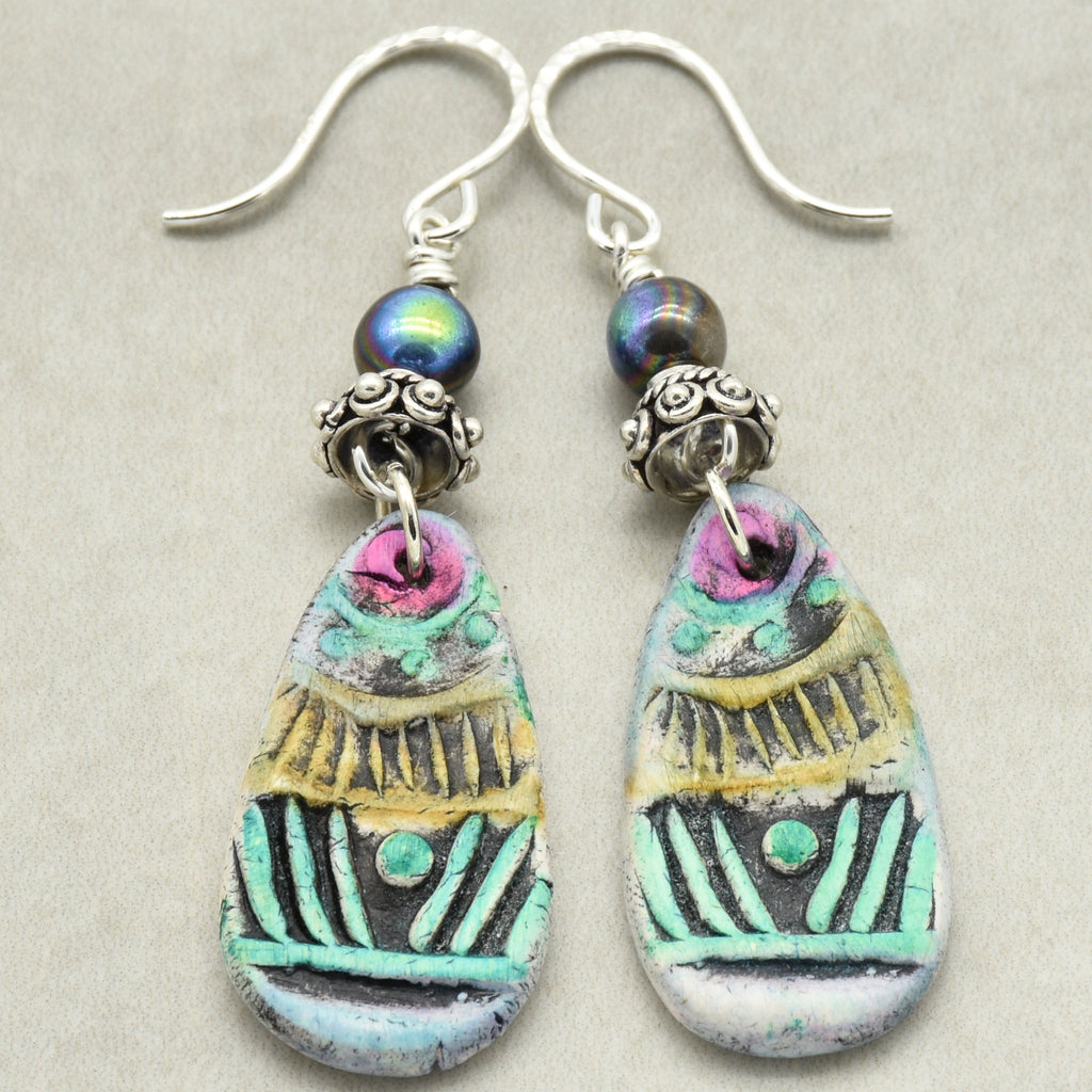 Colorful teardrop earrings with silver hooks on a light gray background