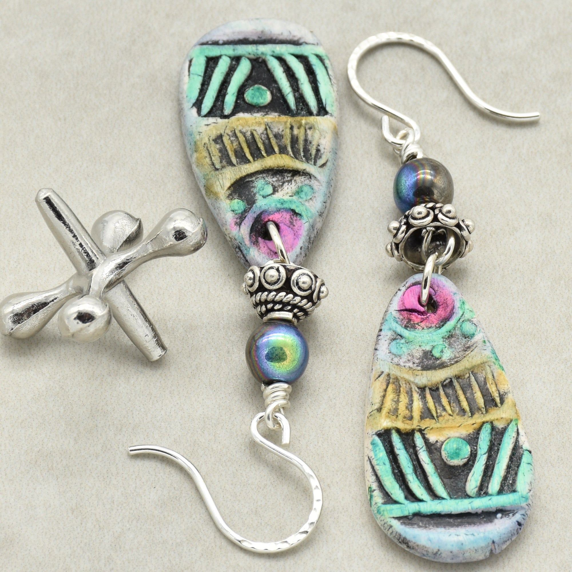 Colorful artisan polymer clay earrings with silver hooks on a light gray background