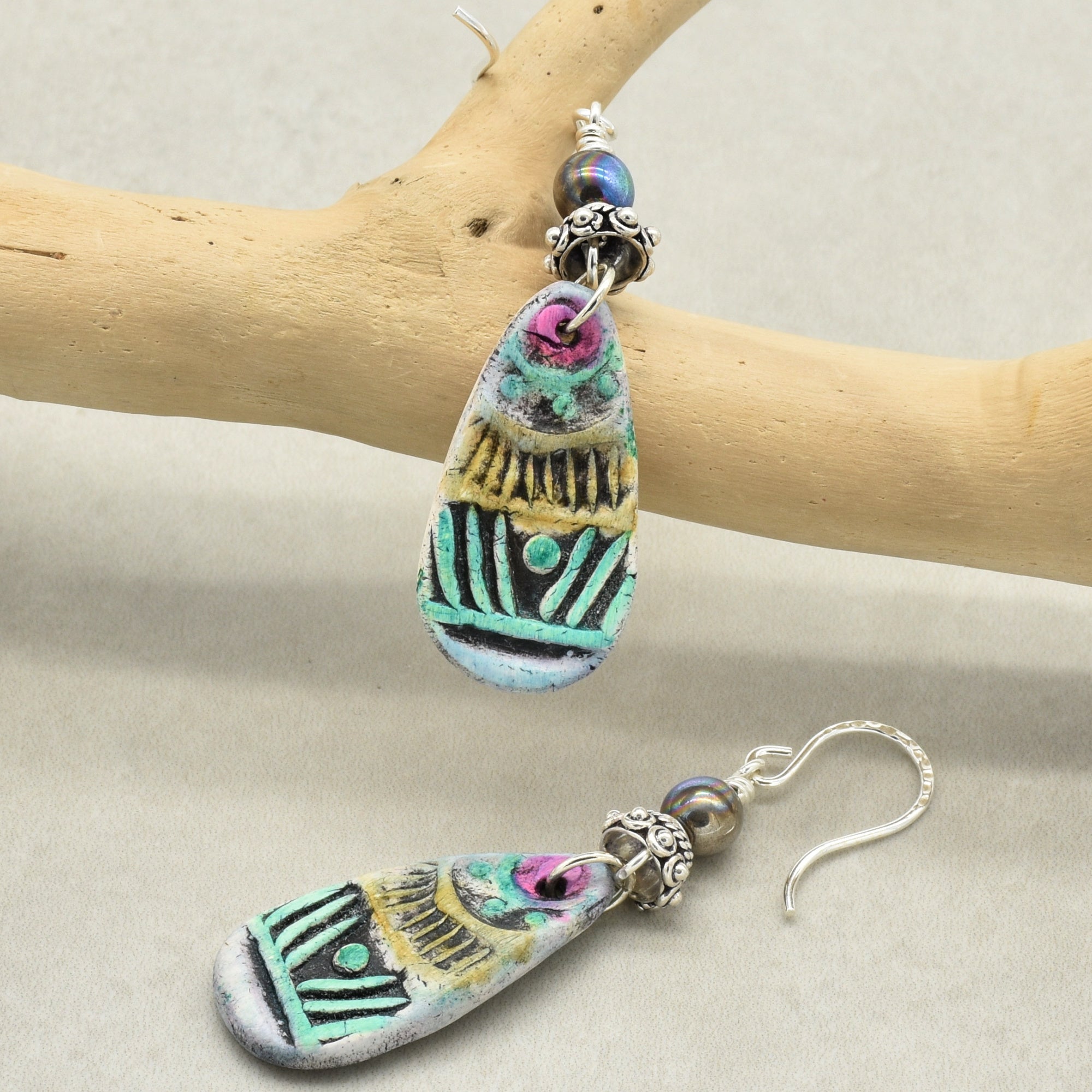 Colorful teardrop-shaped earrings on a wooden branch