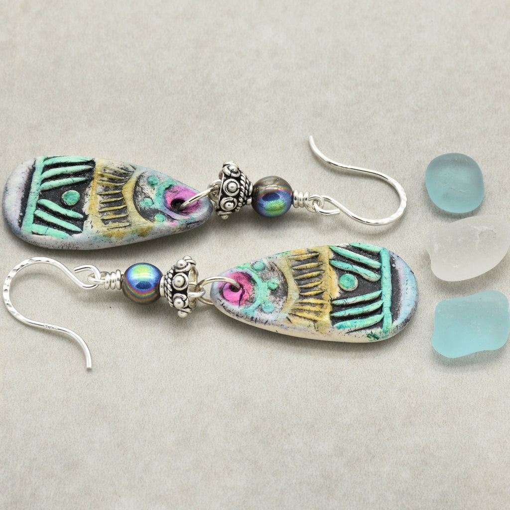 Colorful tribal polymer clay earrings with glass beads on a light gray background