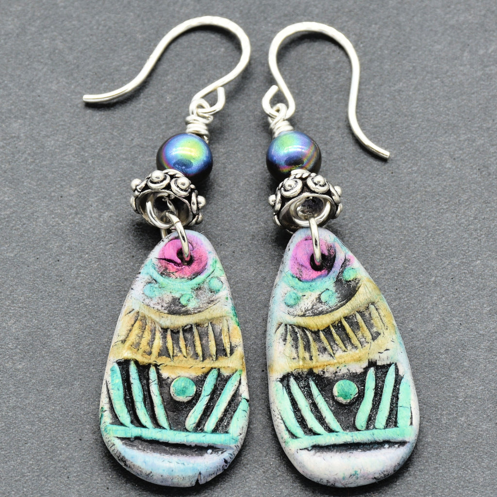 Colorful teardrop-shaped earrings with intricate designs on a gray background