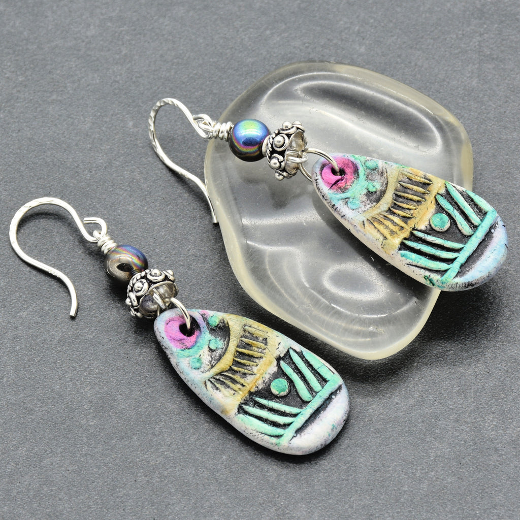 Colorful earrings with tribal designs on a gray background