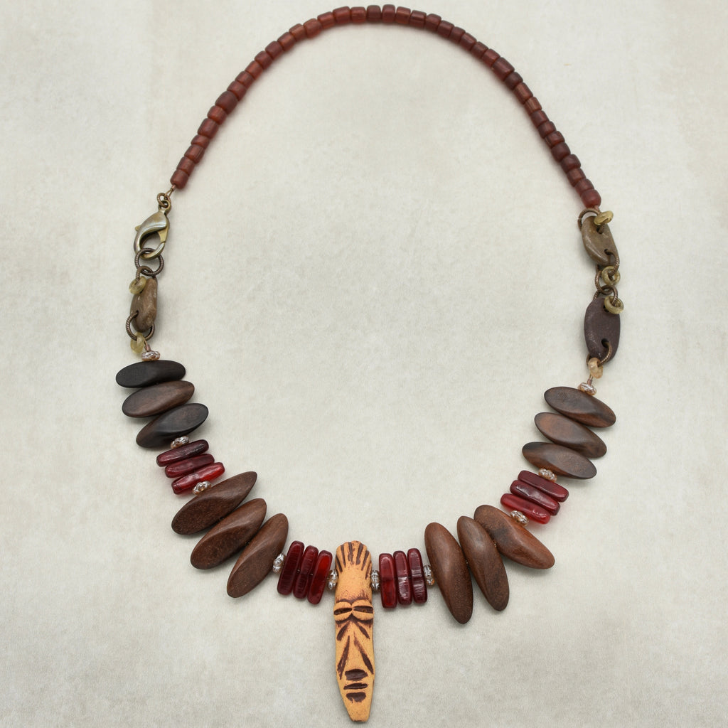 This image shows a necklace. The necklace features a combination of beads, including brown, red, and a central pendant with a carved or painted design.