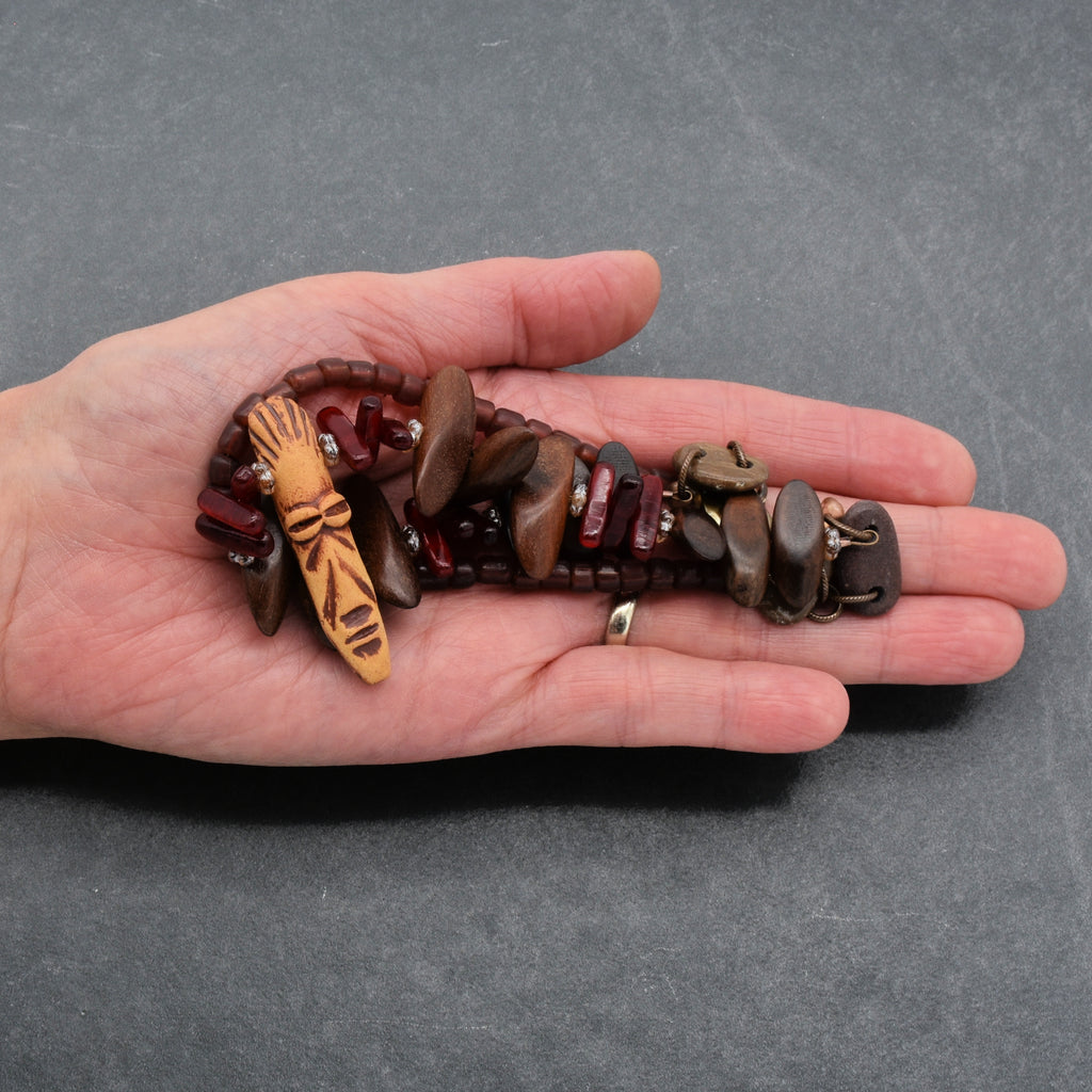 This piece of jewelry appears to be a bracelet. The length and the way it is being held in the hand suggest it is designed to wrap around a wrist. The presence of a clasp further confirms it as a bracelet rather than a necklace or earring.